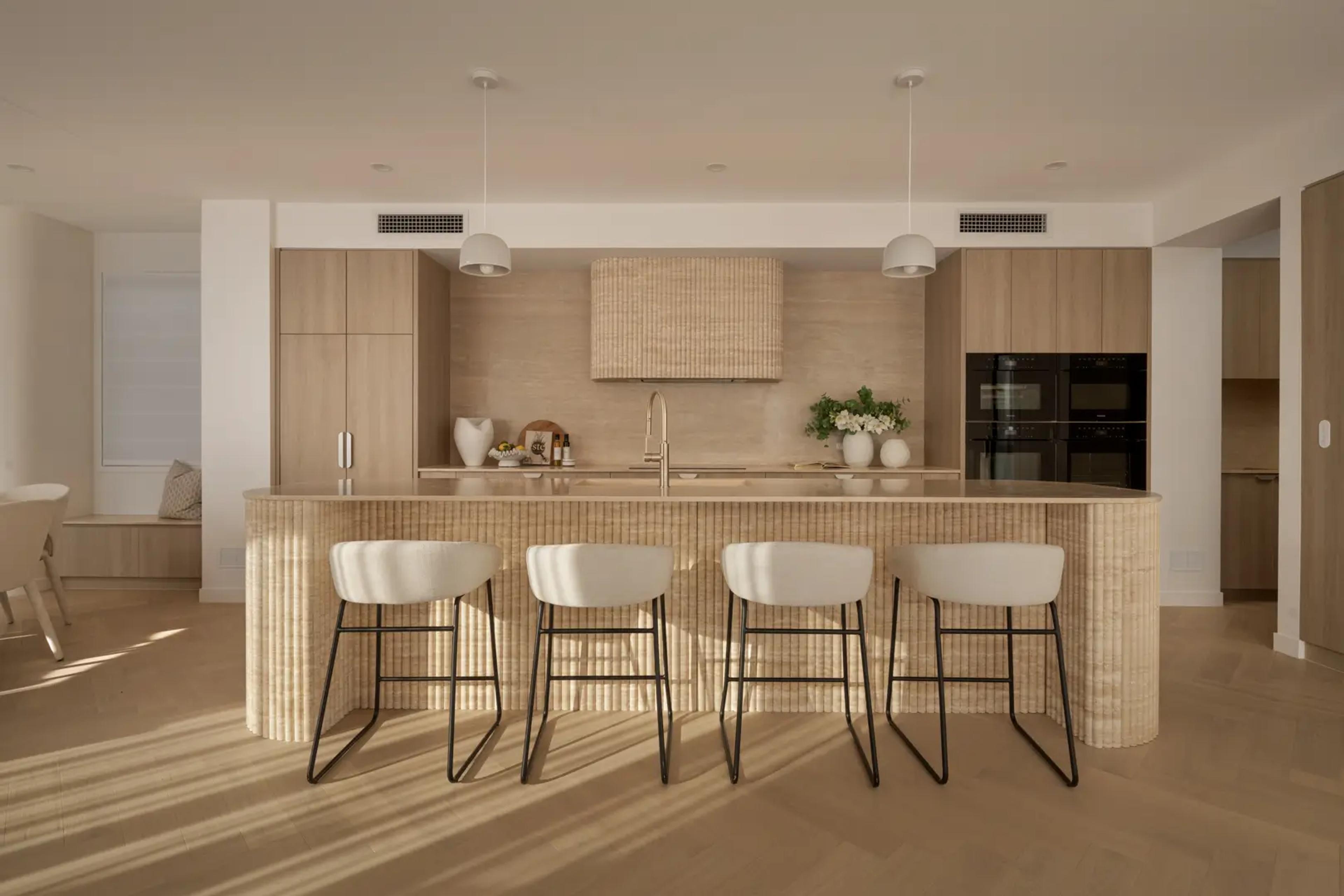 Kitchen island with white stools and integrated ovens