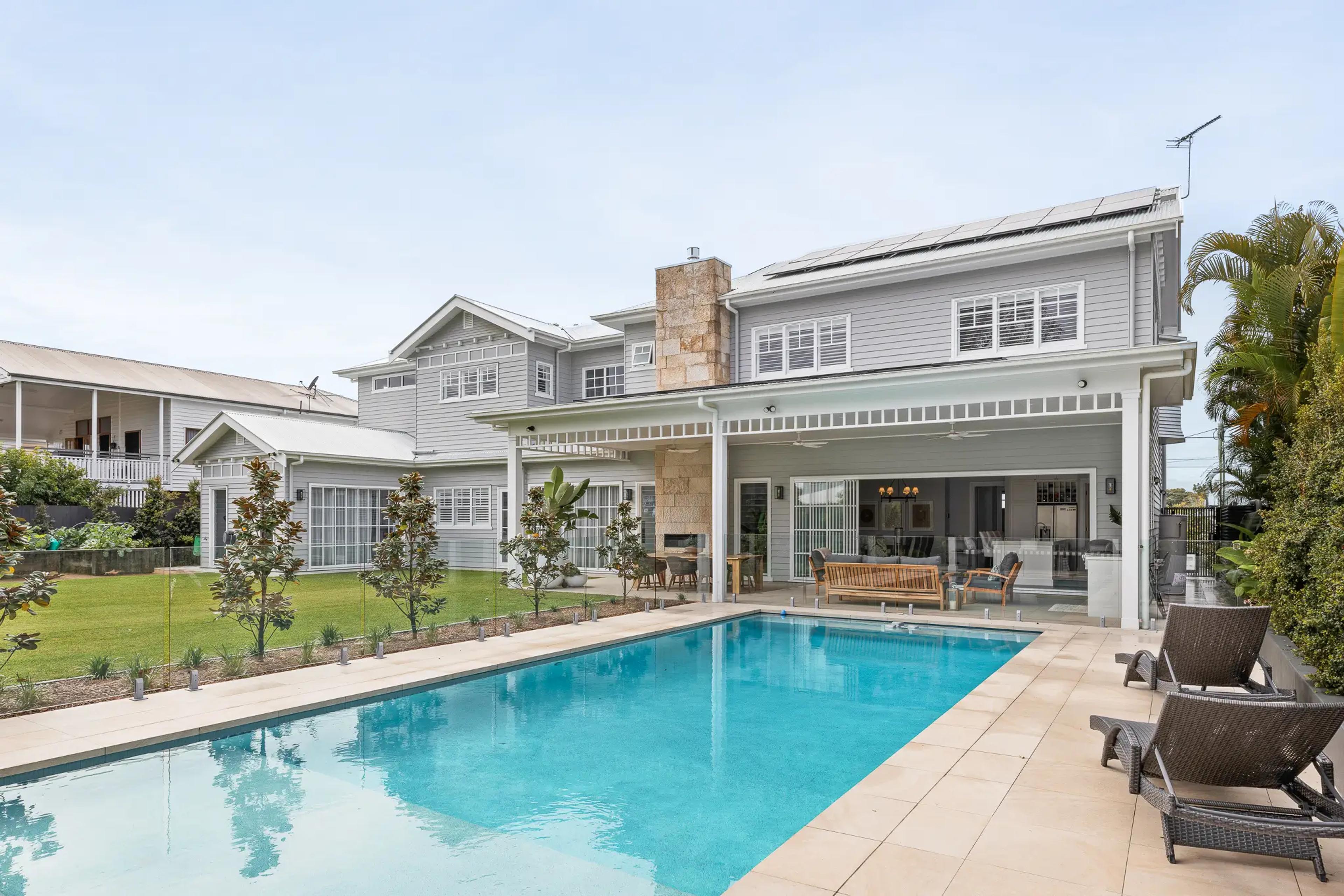 Rear elevation of grey two storey home with swimming pool and terrace