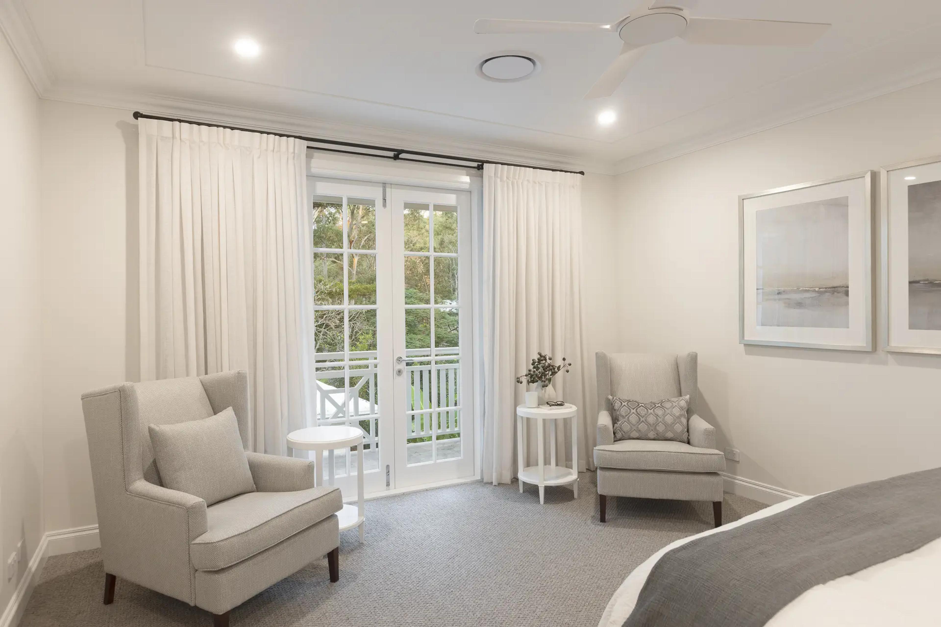 Neutral bedroom with french doors opening to a balcony and framed artwork