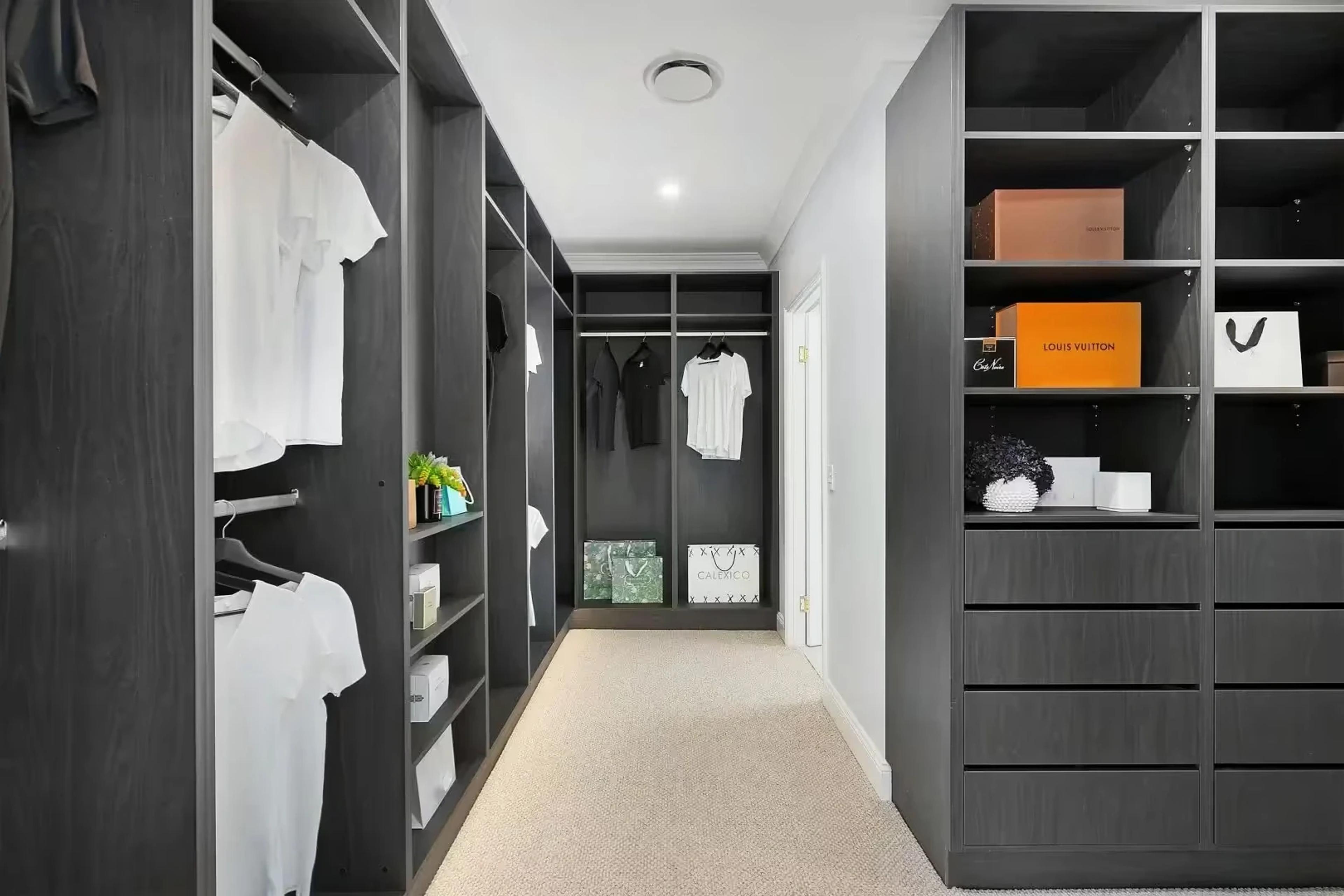 Walk in wardrobe with dark timber shelving and drawers