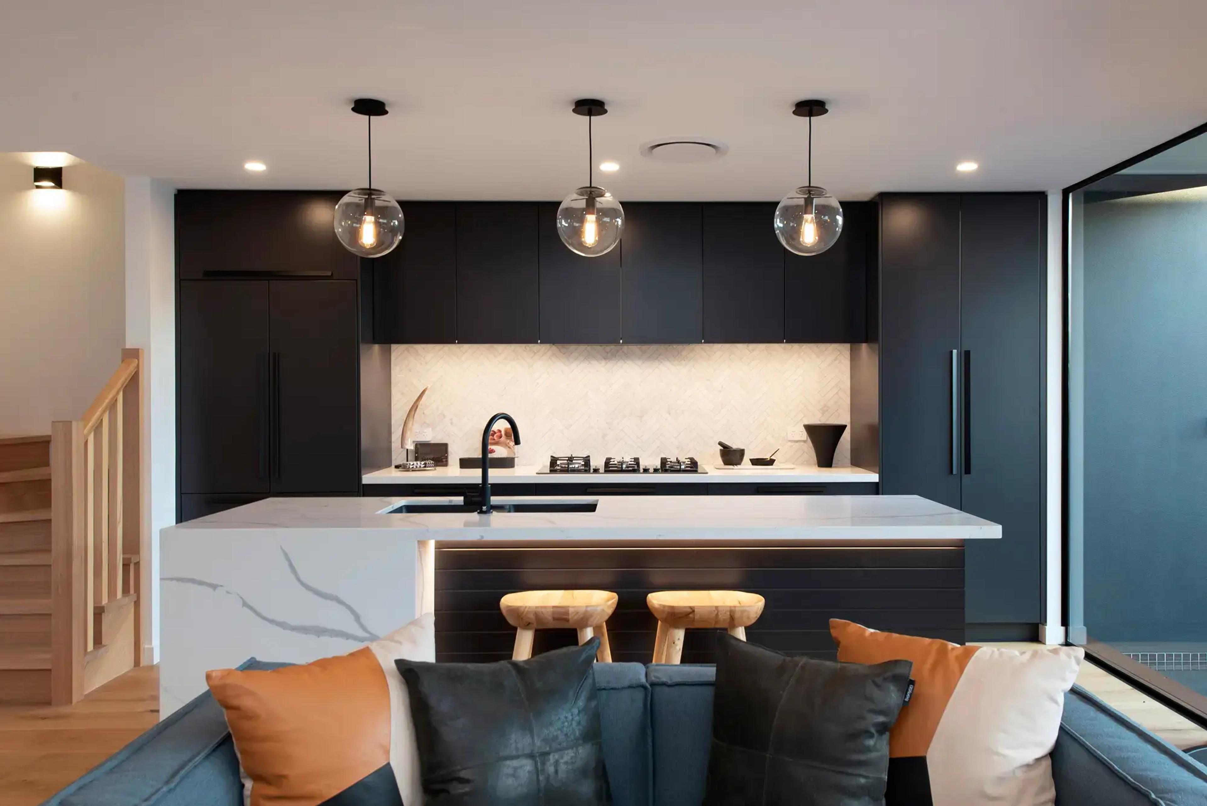 Dark kitchen with island bar and floating staircase