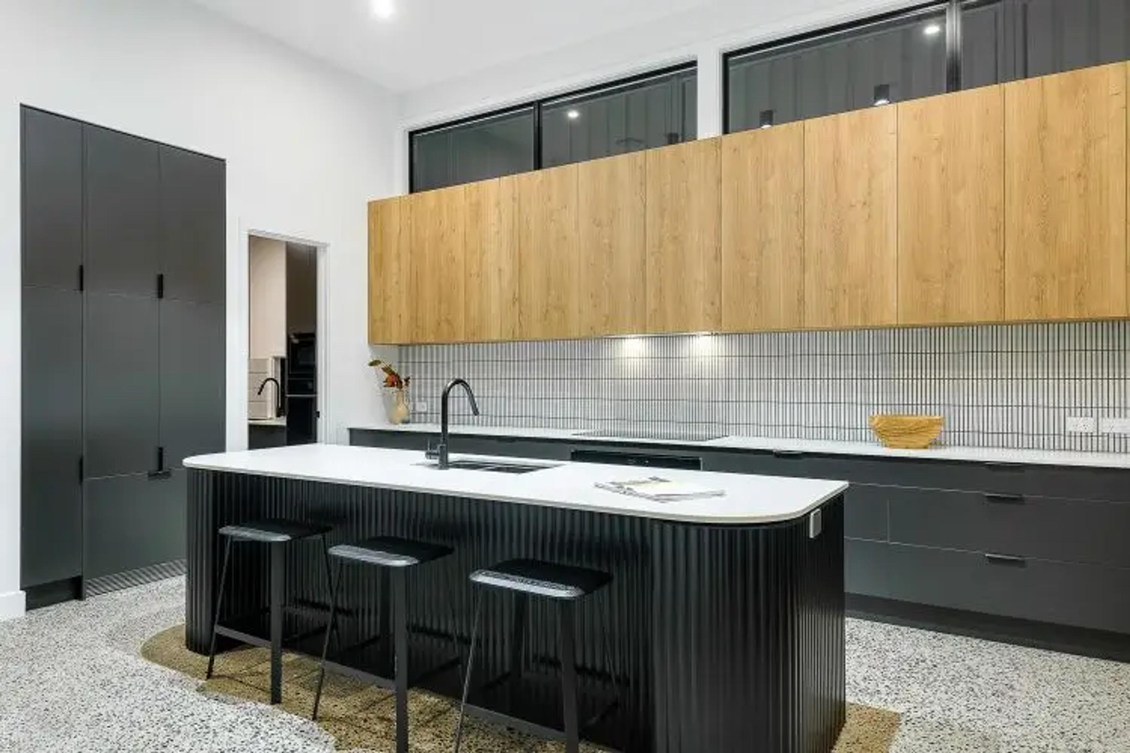 Kitchen with timber cabinetry and fluted black island bench