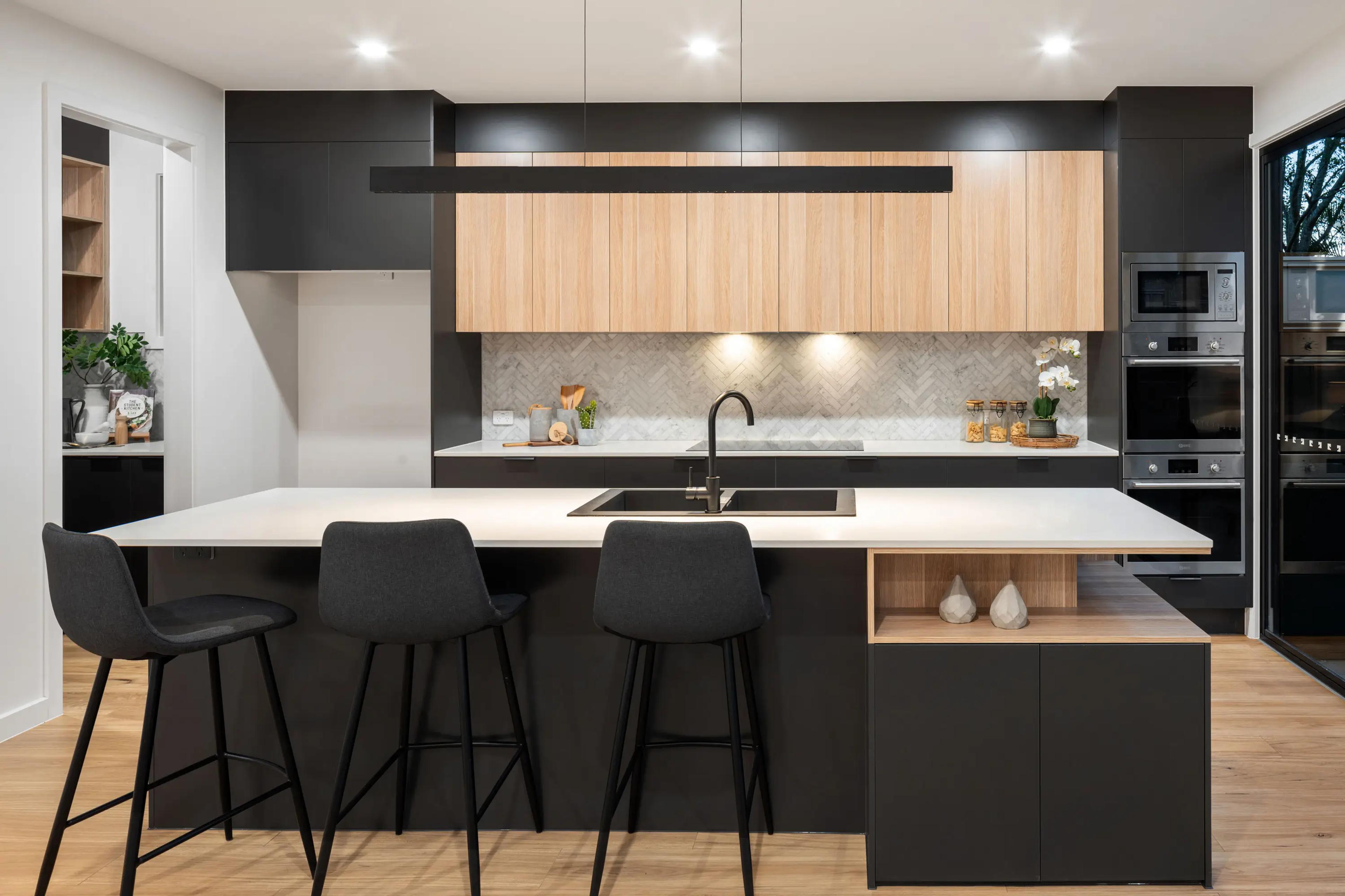 Kitchen with timber cabinetry, stone island and black joinery