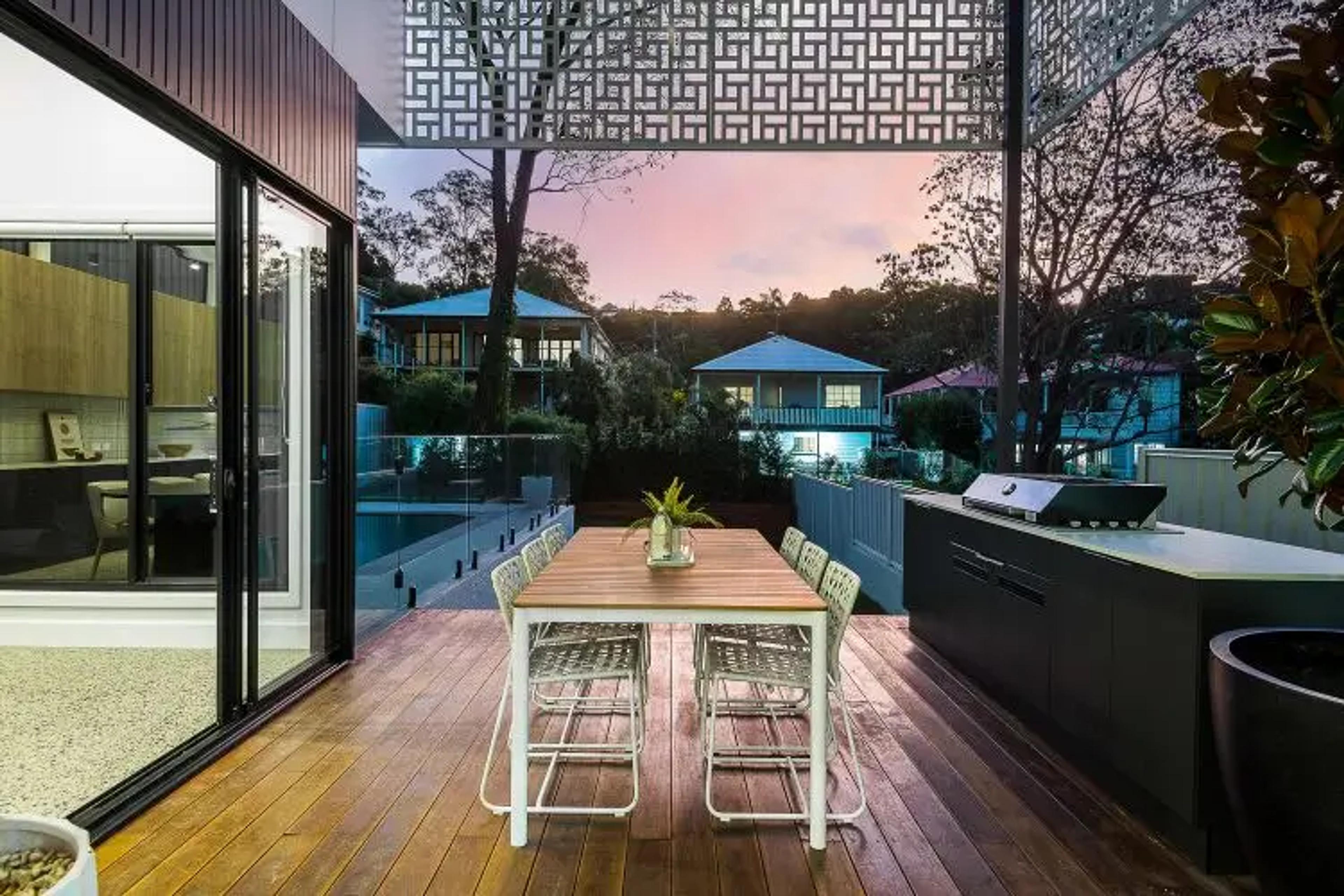 Timber deck dining area overlooking pool and suburb at dusk