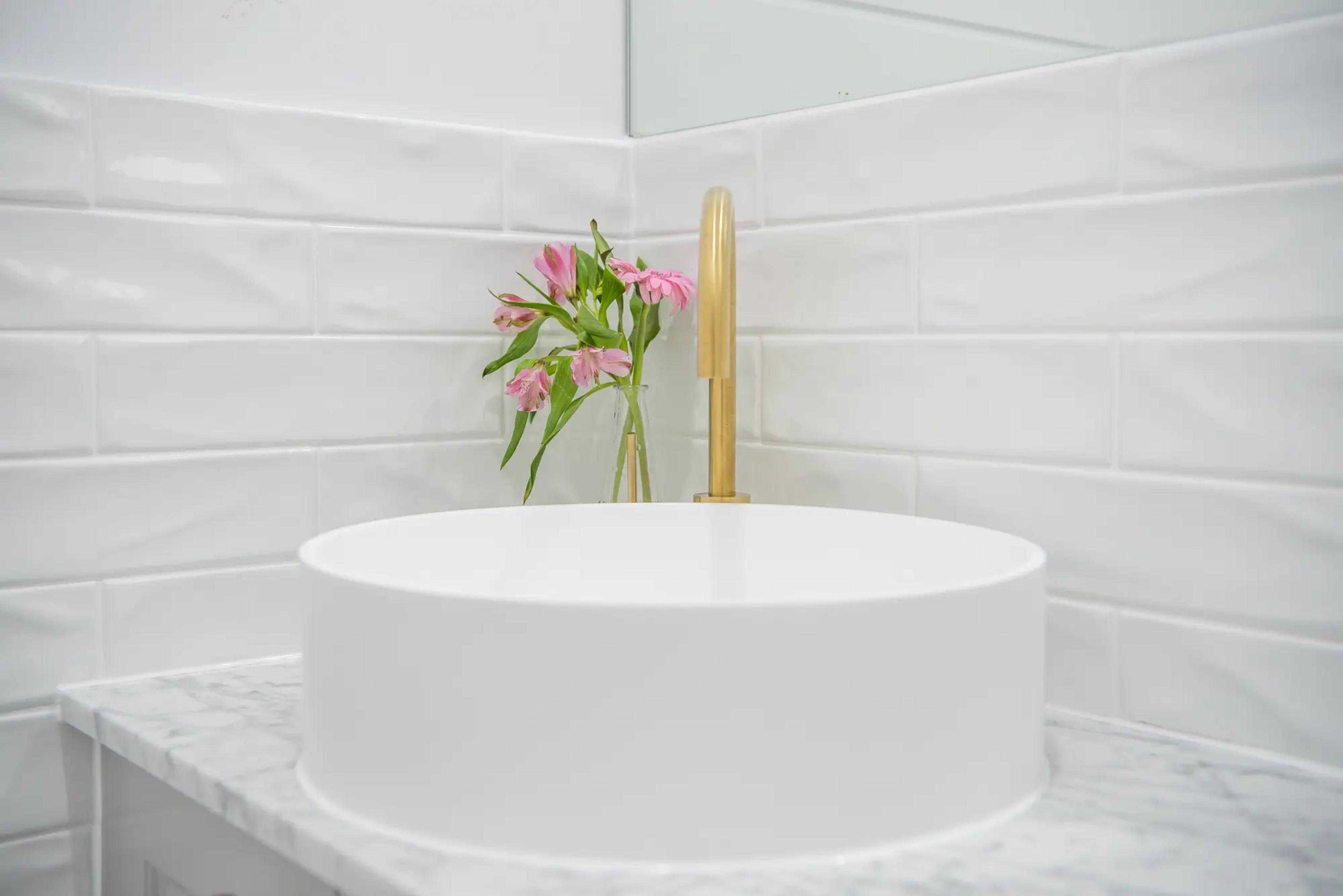Round white basin with brass tap and pink flowers