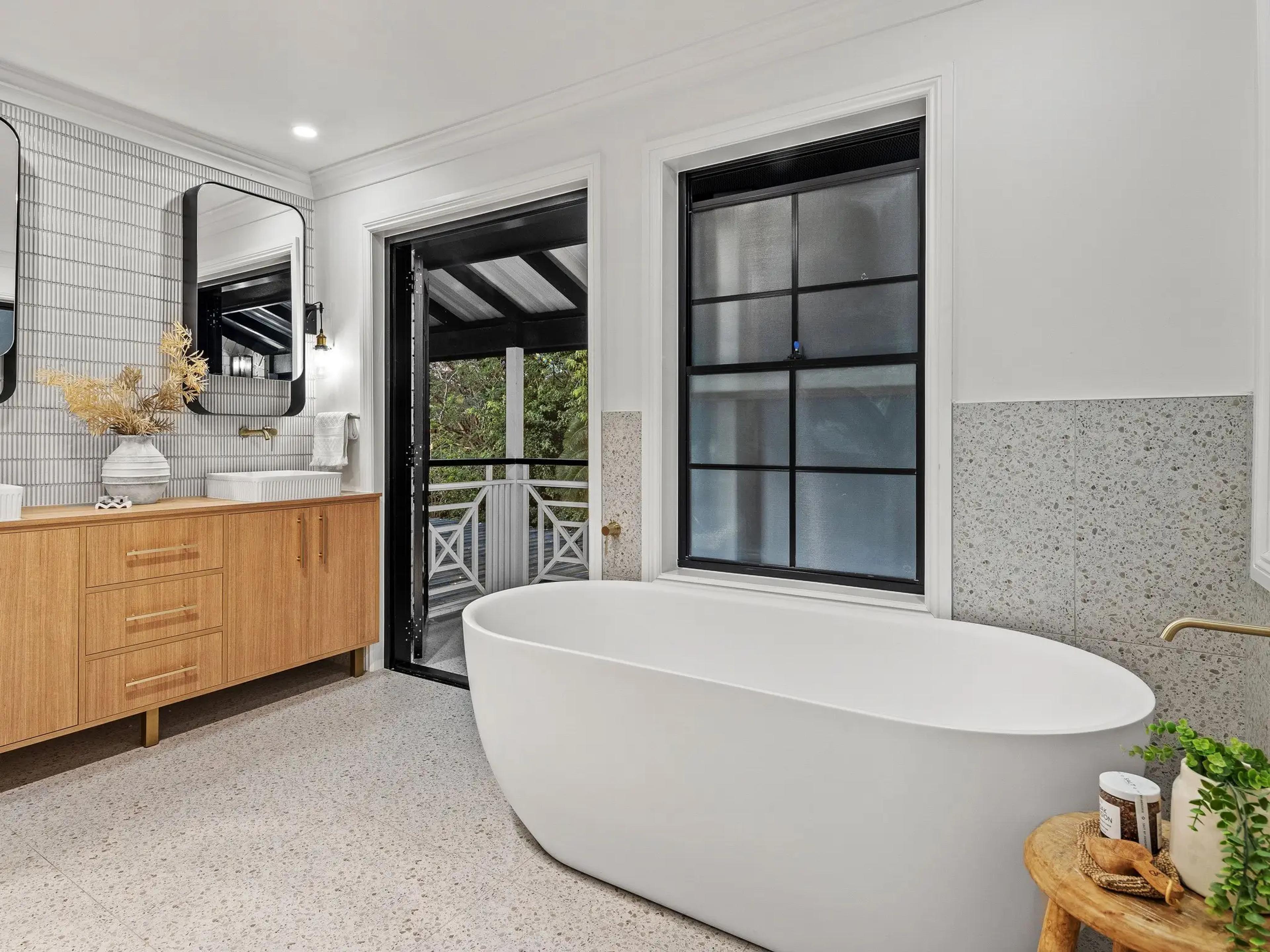 Bathroom with freestanding bath beside black framed window