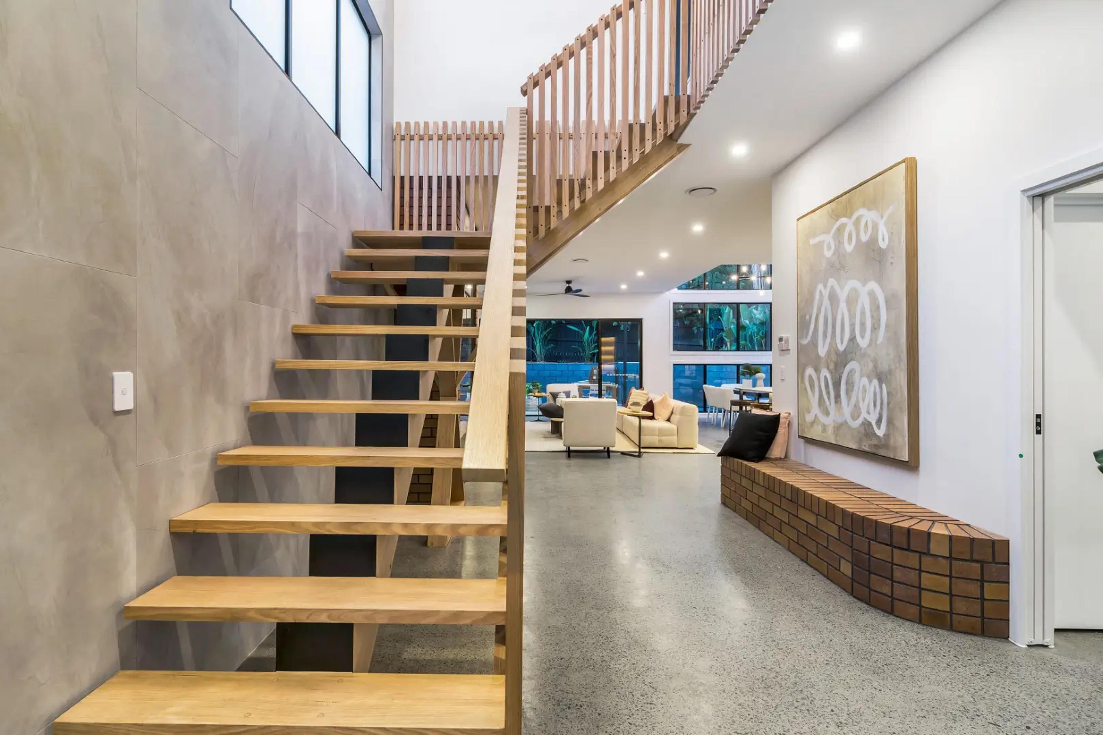 Timber staircase and polished concrete entry toward open living area