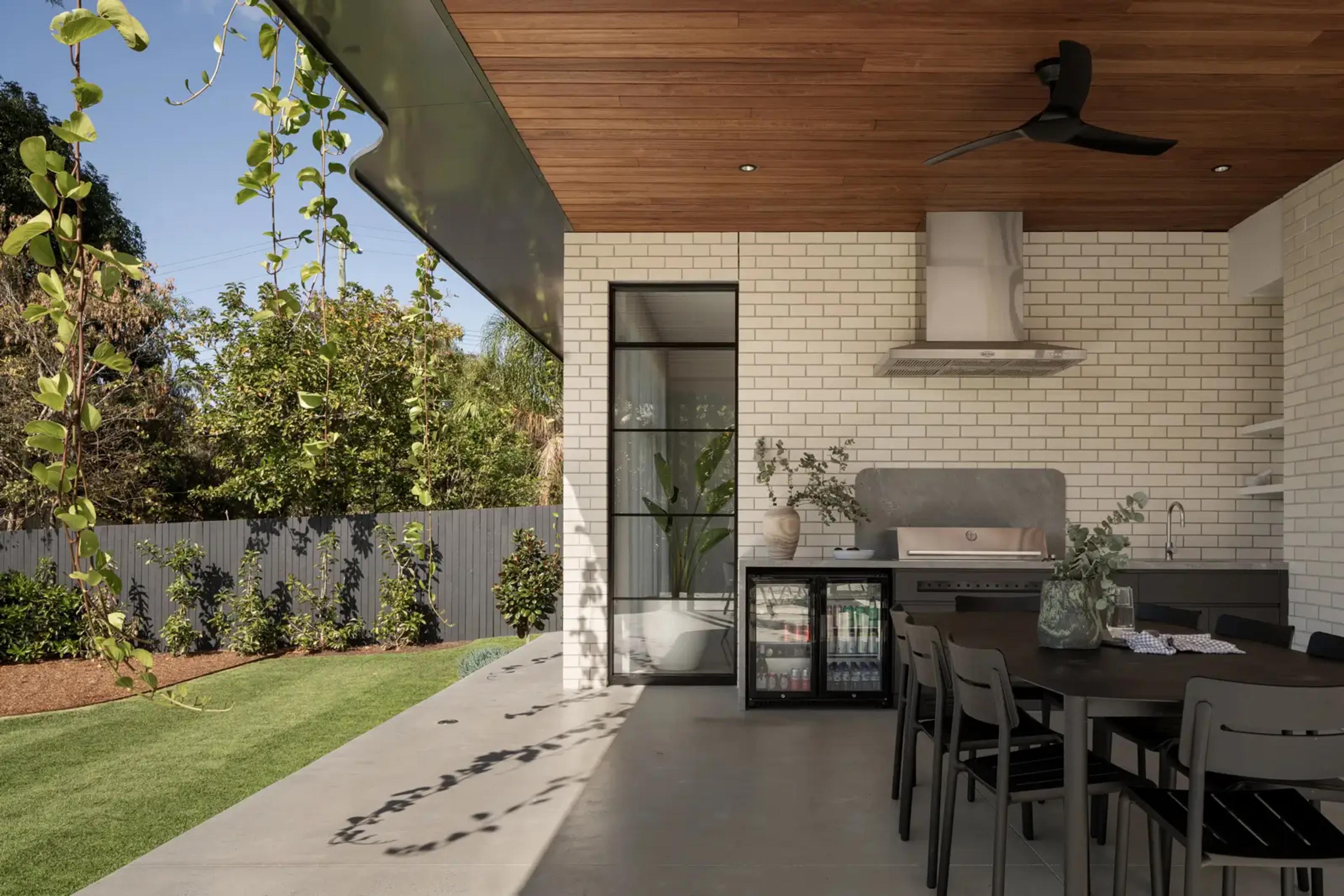Covered outdoor kitchen with barbecue, timber ceiling and dining table