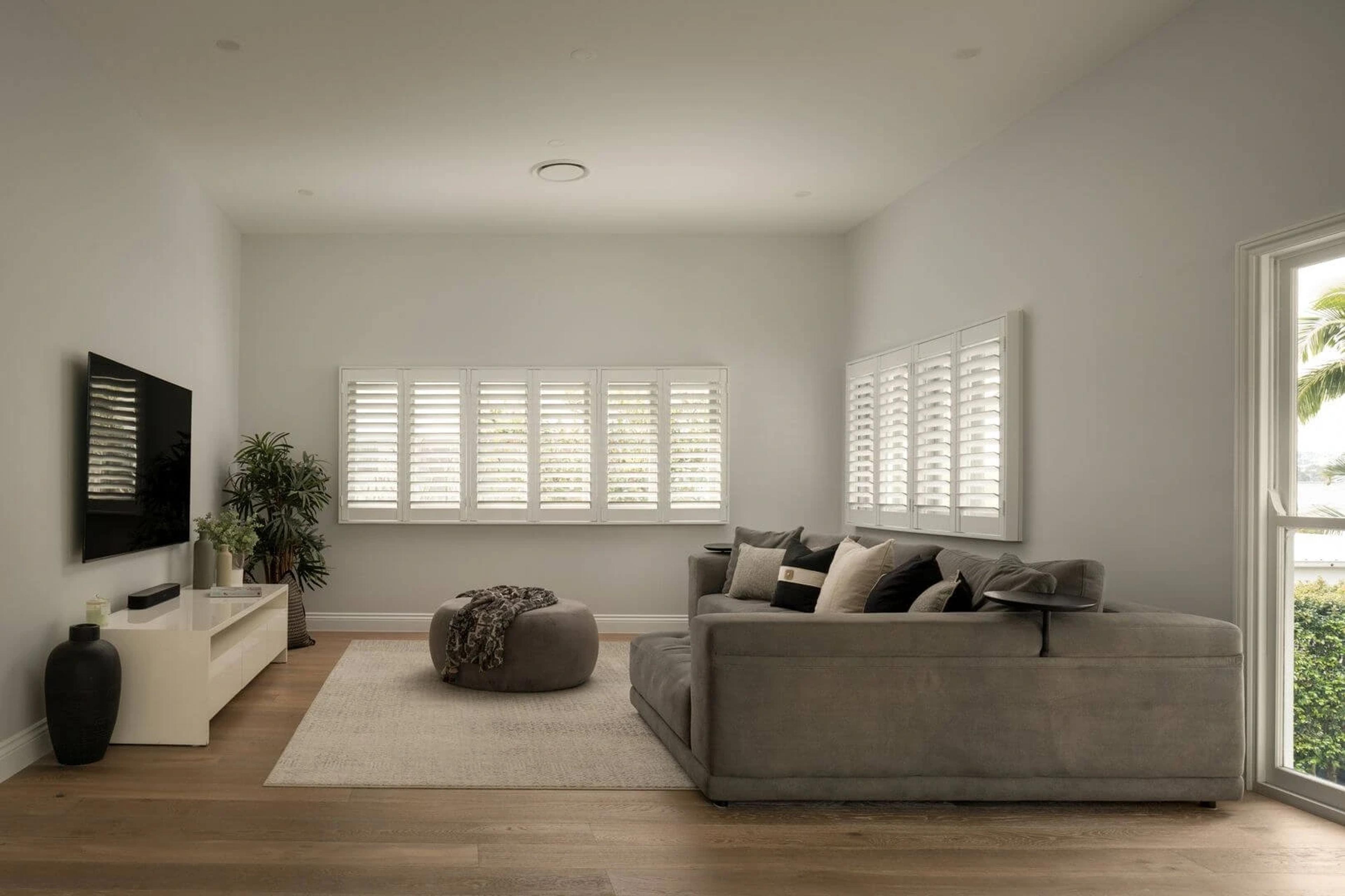 Media room with grey lounge, wall television and plantation shutters