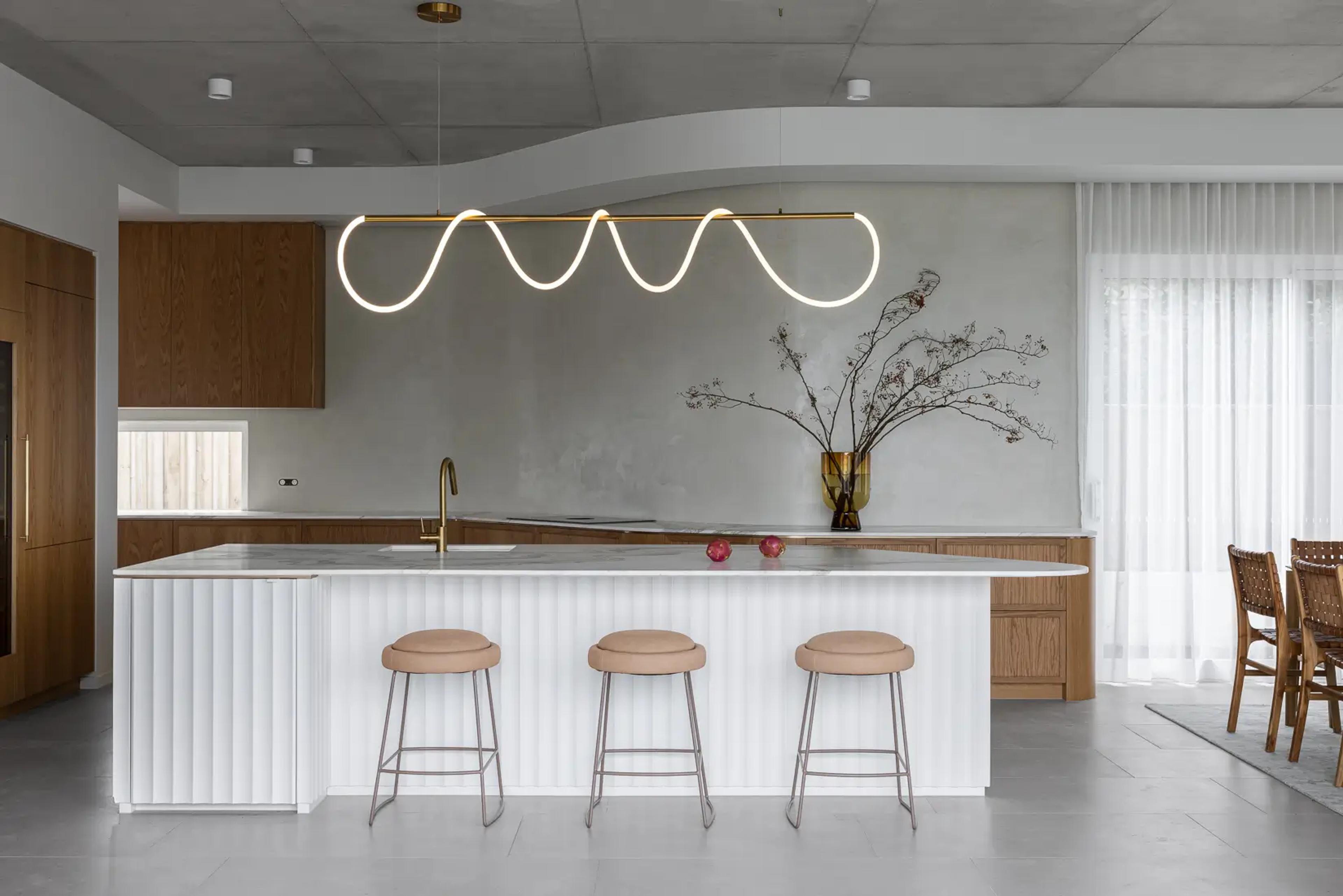 Kitchen island with three stools under wavy pendant light