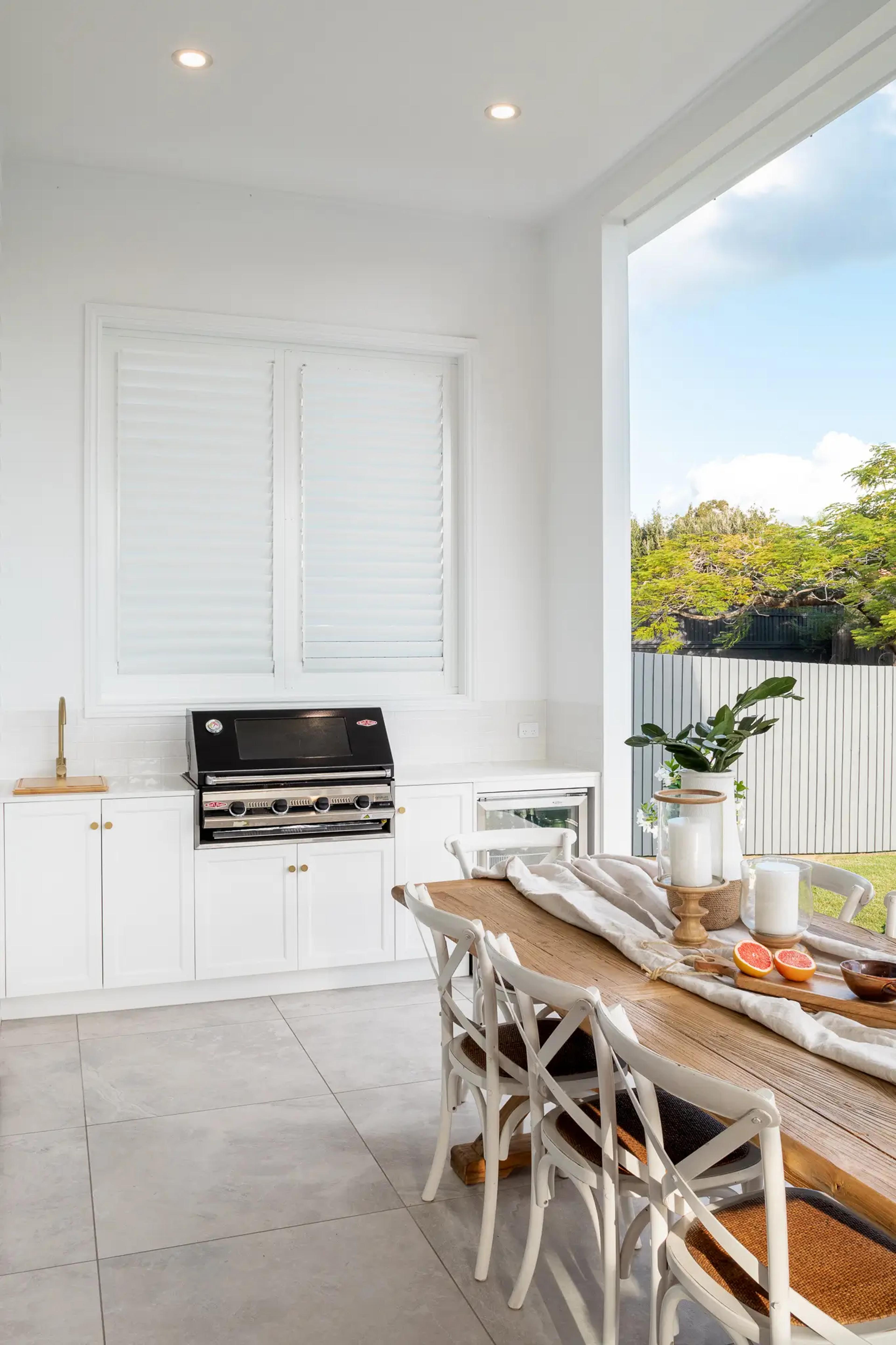 Outdoor kitchen with barbecue beside timber dining table
