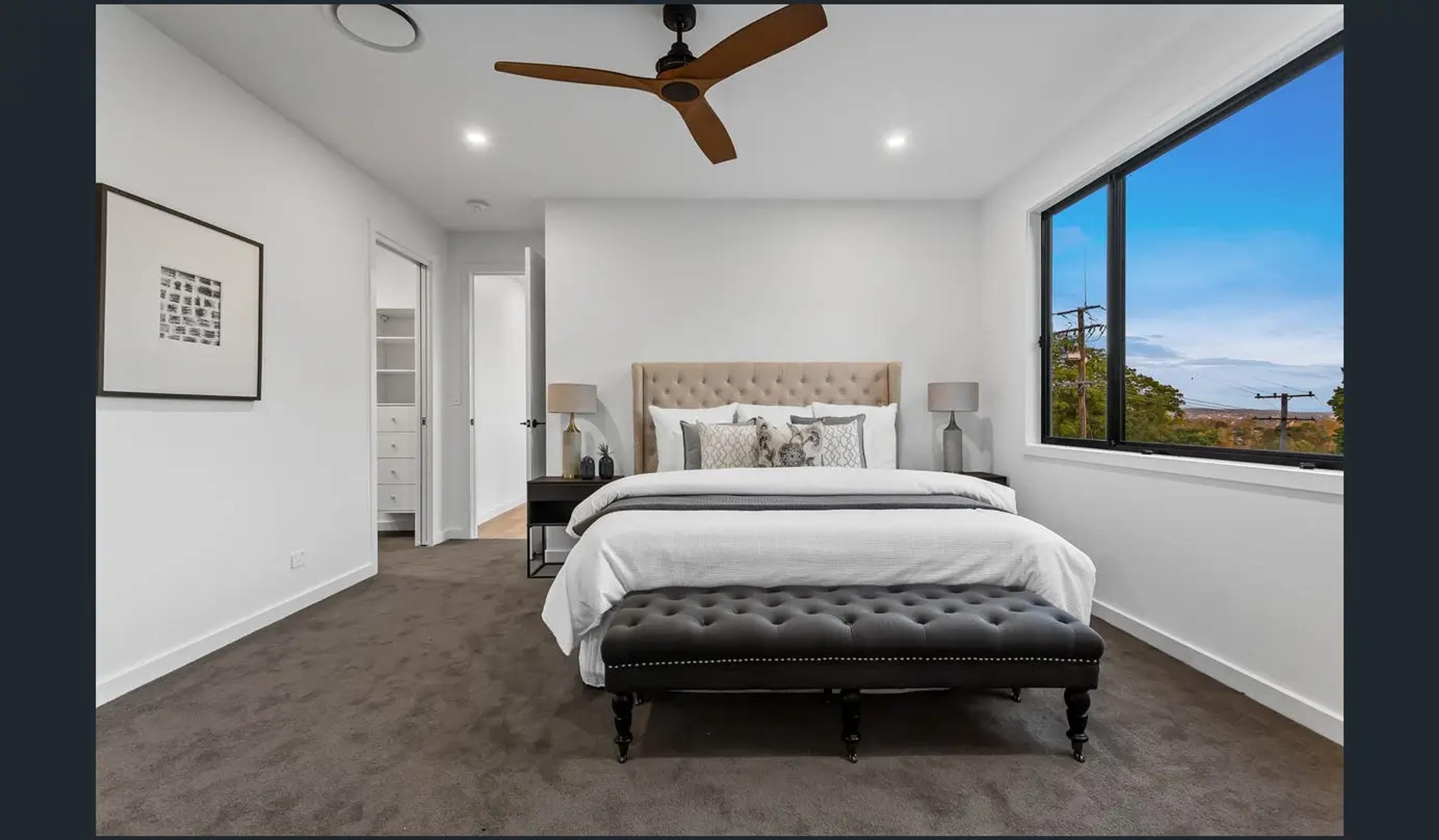 Carpeted bedroom with upholstered bed and distant view