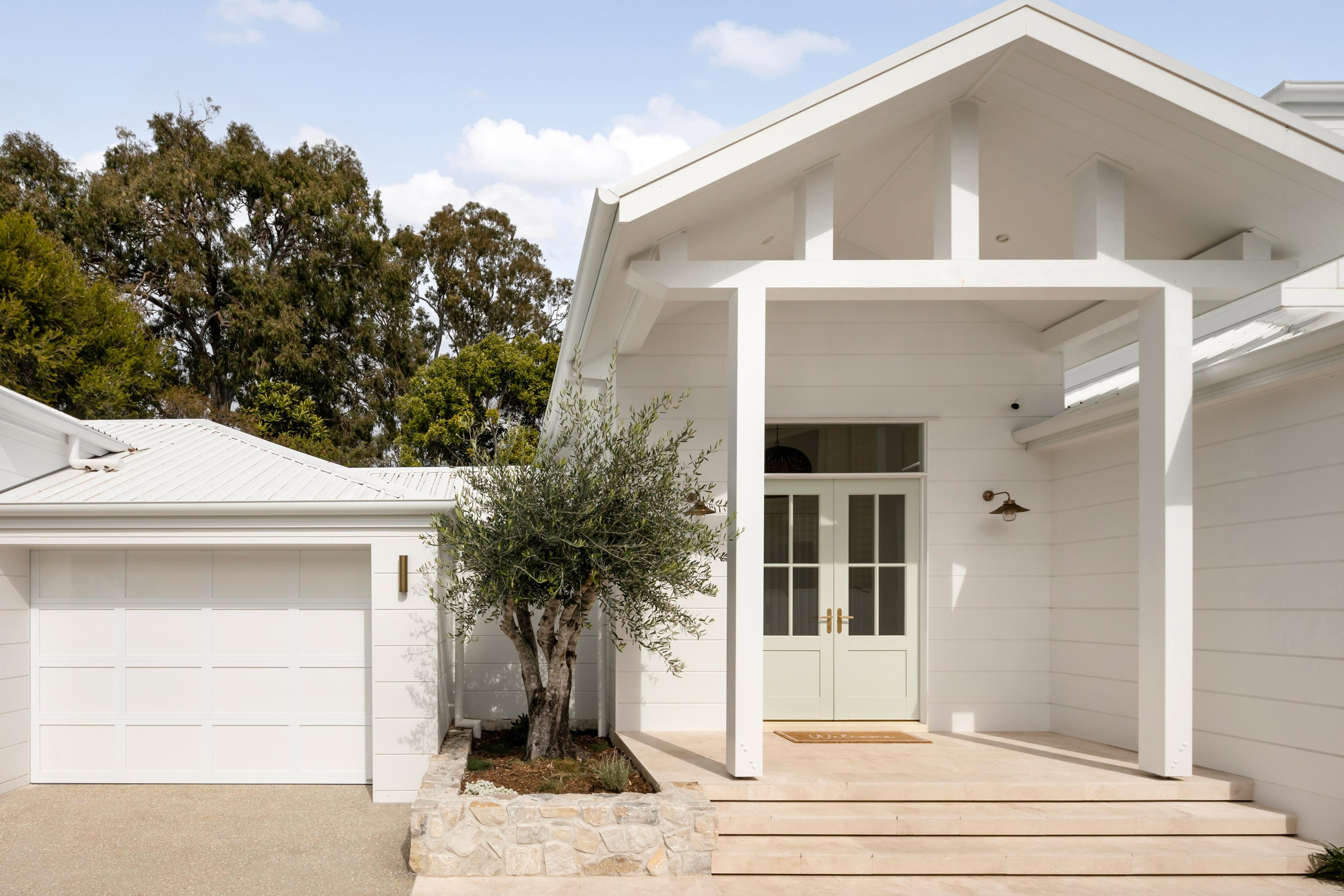 White home entrance with gabled porch and garage