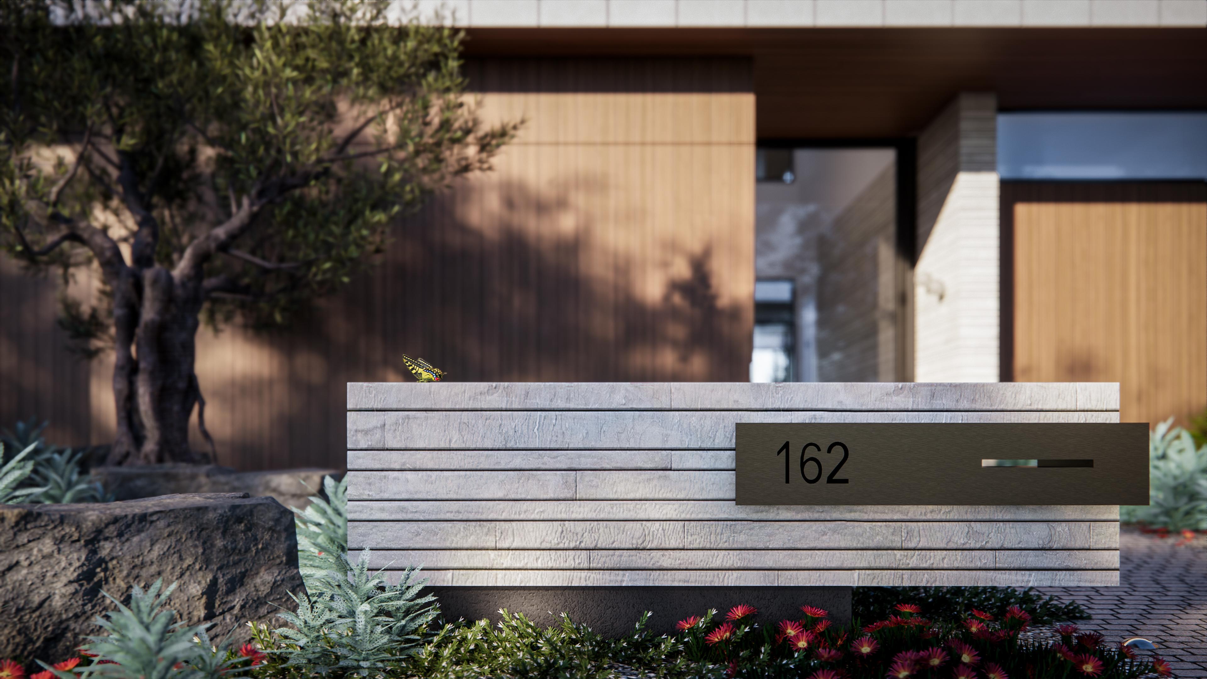 Detail of the stone entry wall with a bronze letterbox marked one hundred and sixty two and an olive tree