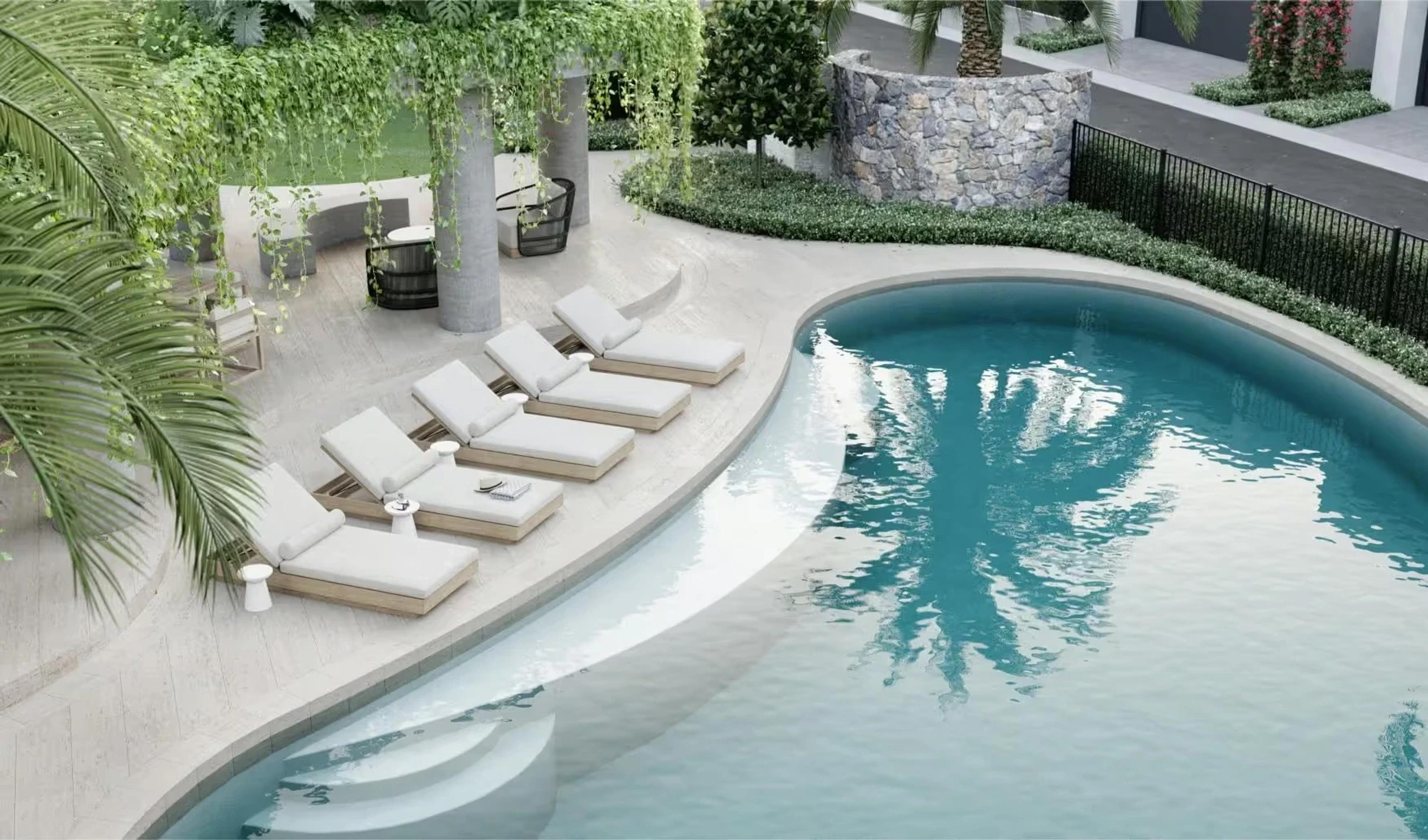 Aerial view of curved pool with sun loungers and landscaping
