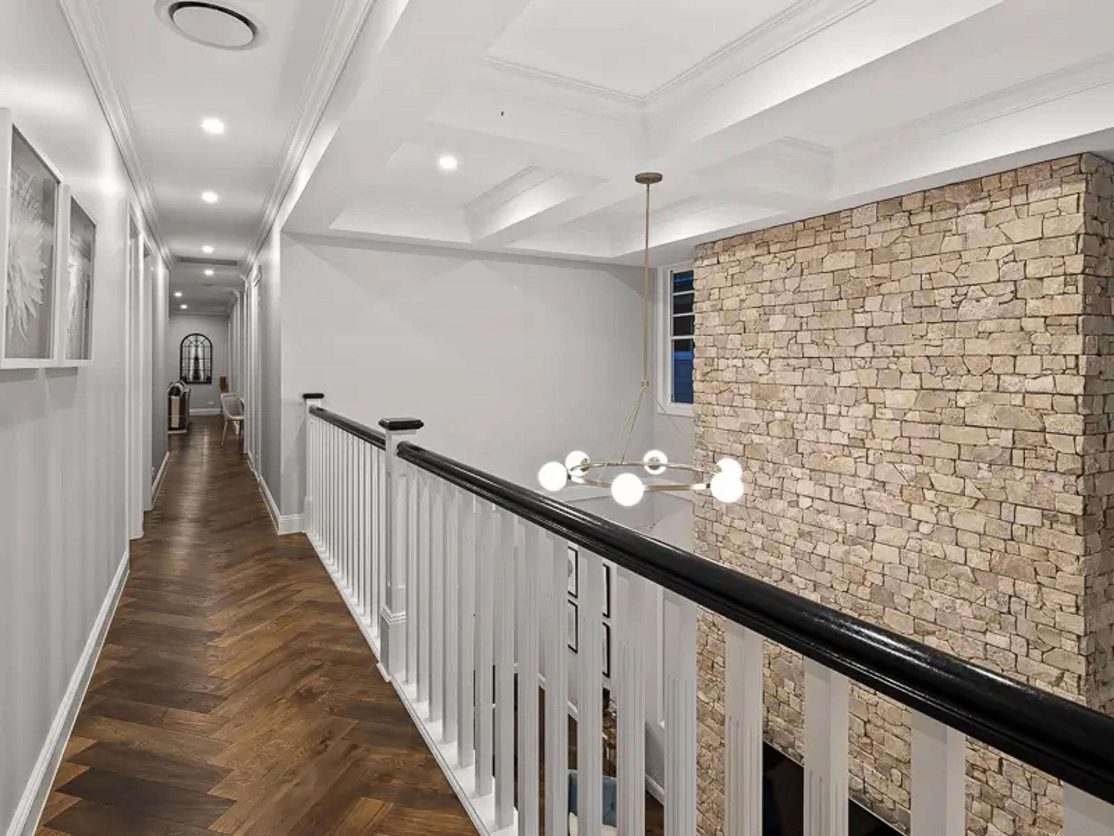 Upstairs landing with white balustrade and stone feature wall