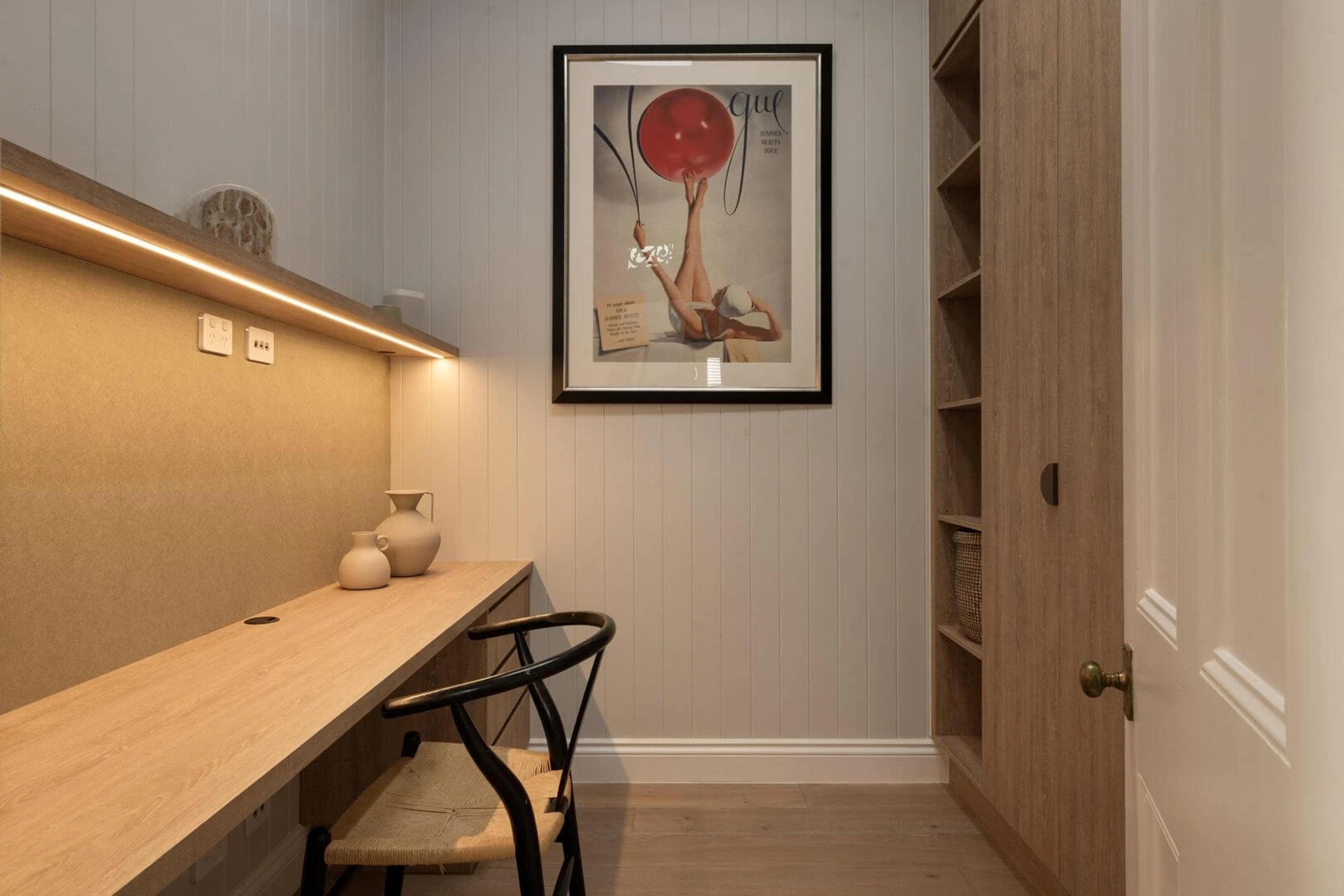 Study nook with timber desk, rattan chair and framed artwork