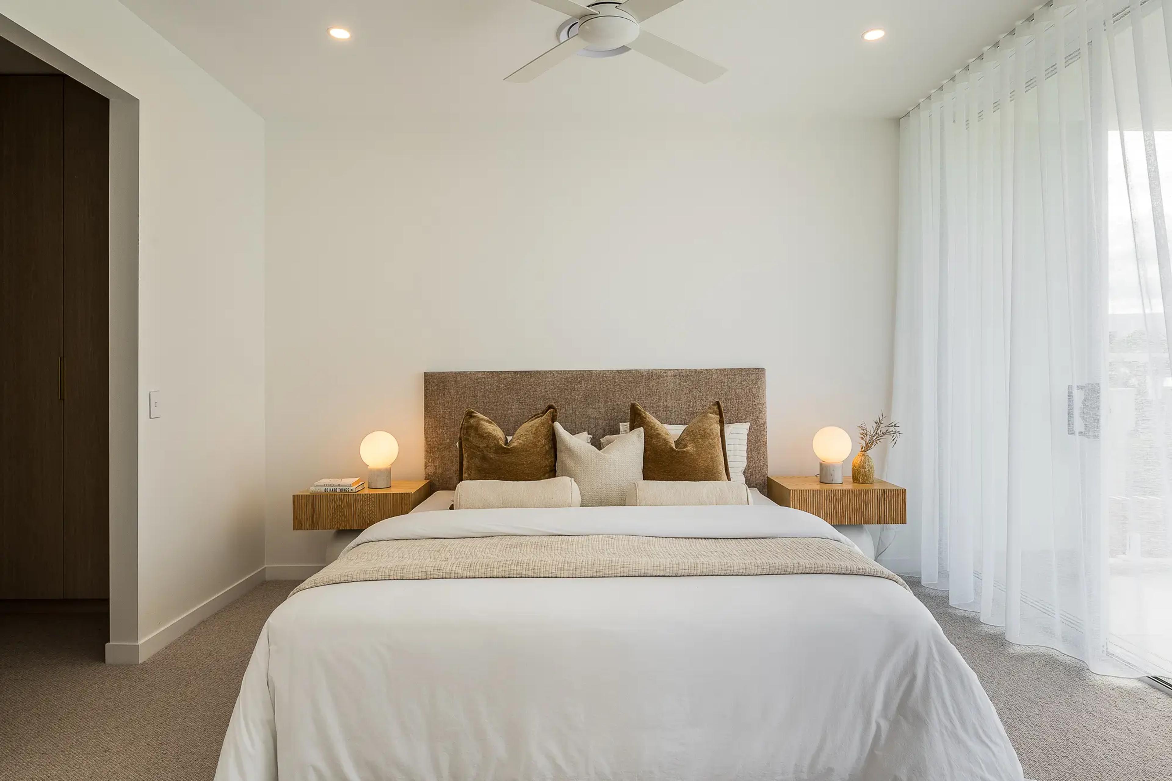 Bedroom with upholstered bedhead and sheer curtains