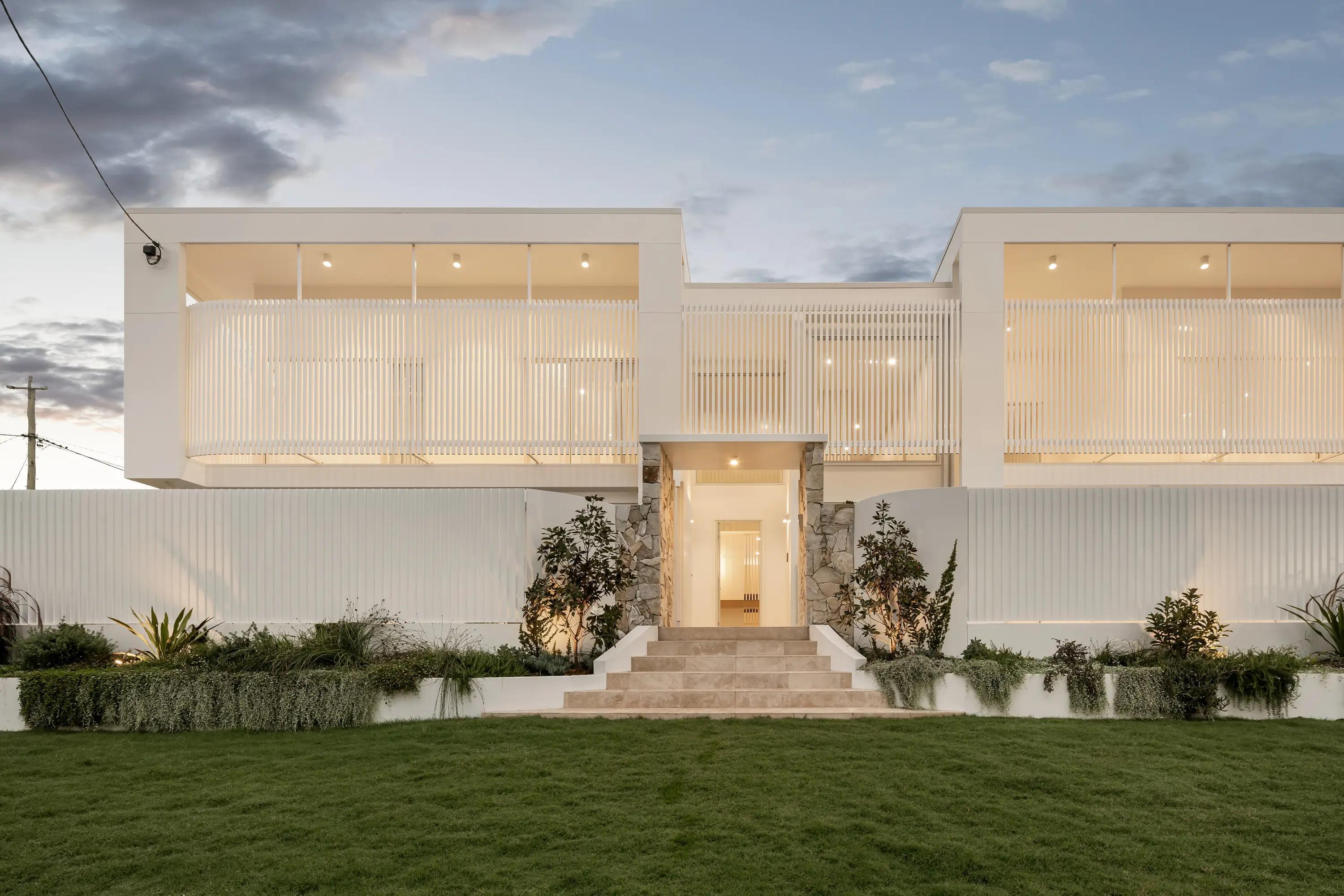 Full white home front facade with entry steps and lawn at dusk