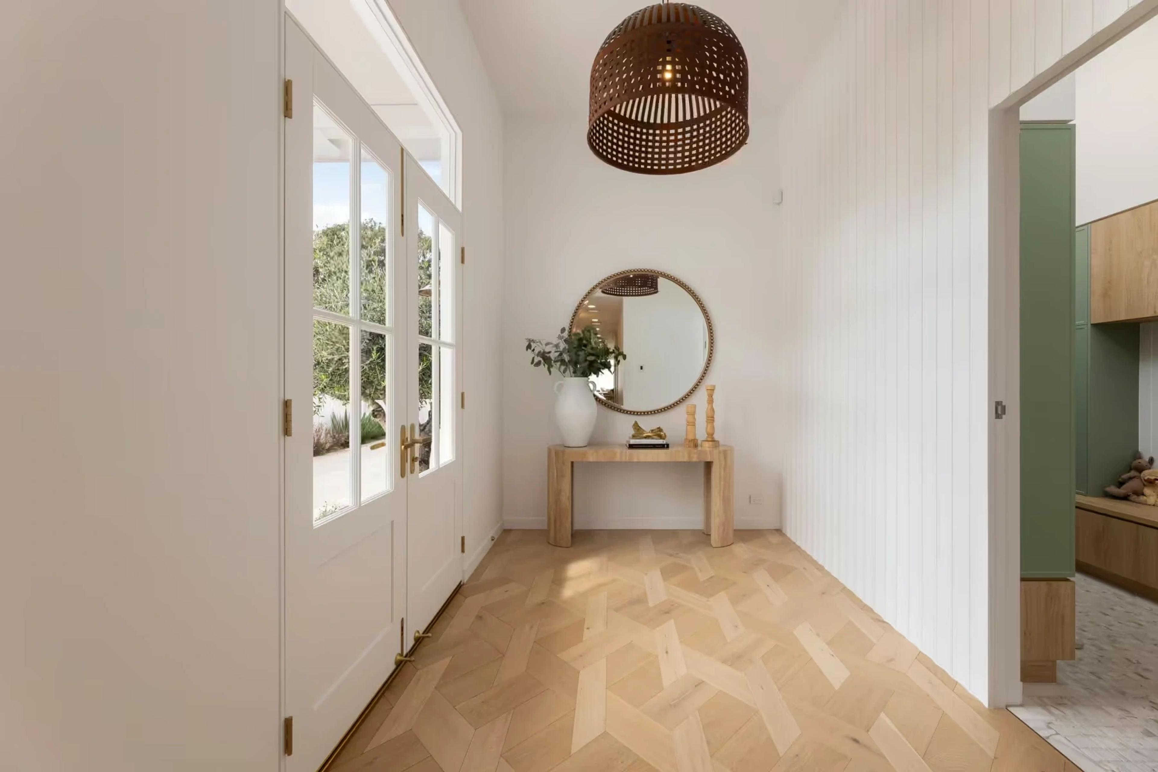 Entry hall with console table, round mirror and parquetry floor