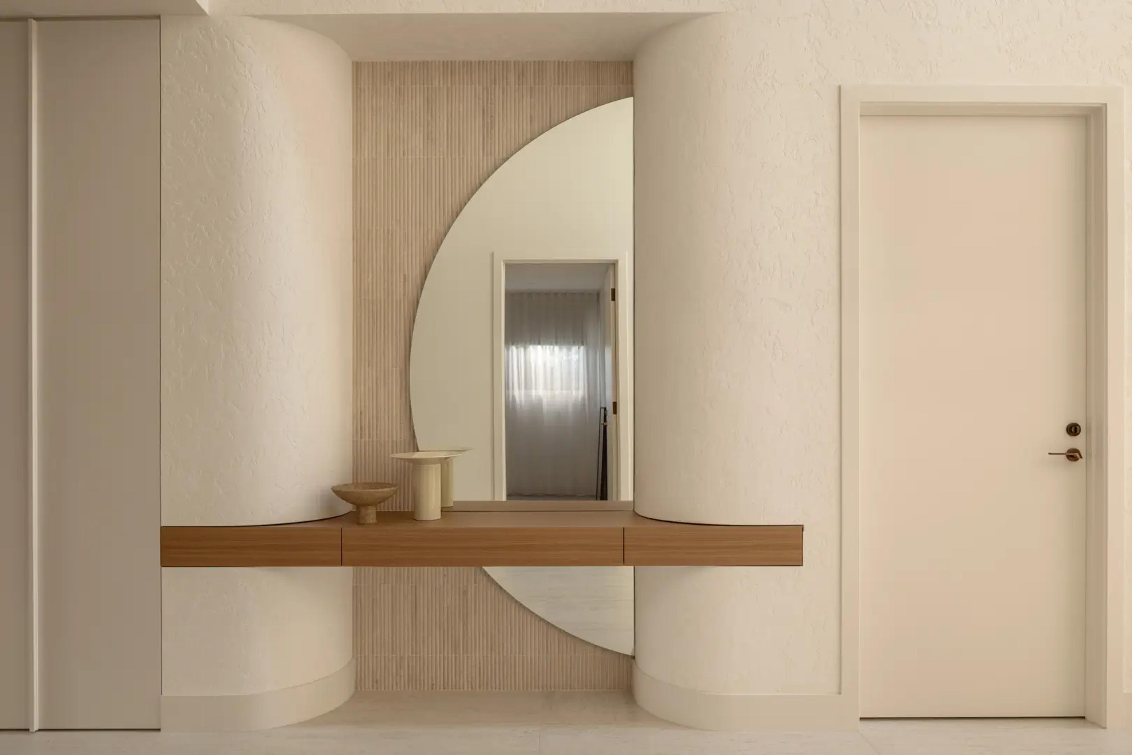 Curved entry nook with round mirror and floating shelf