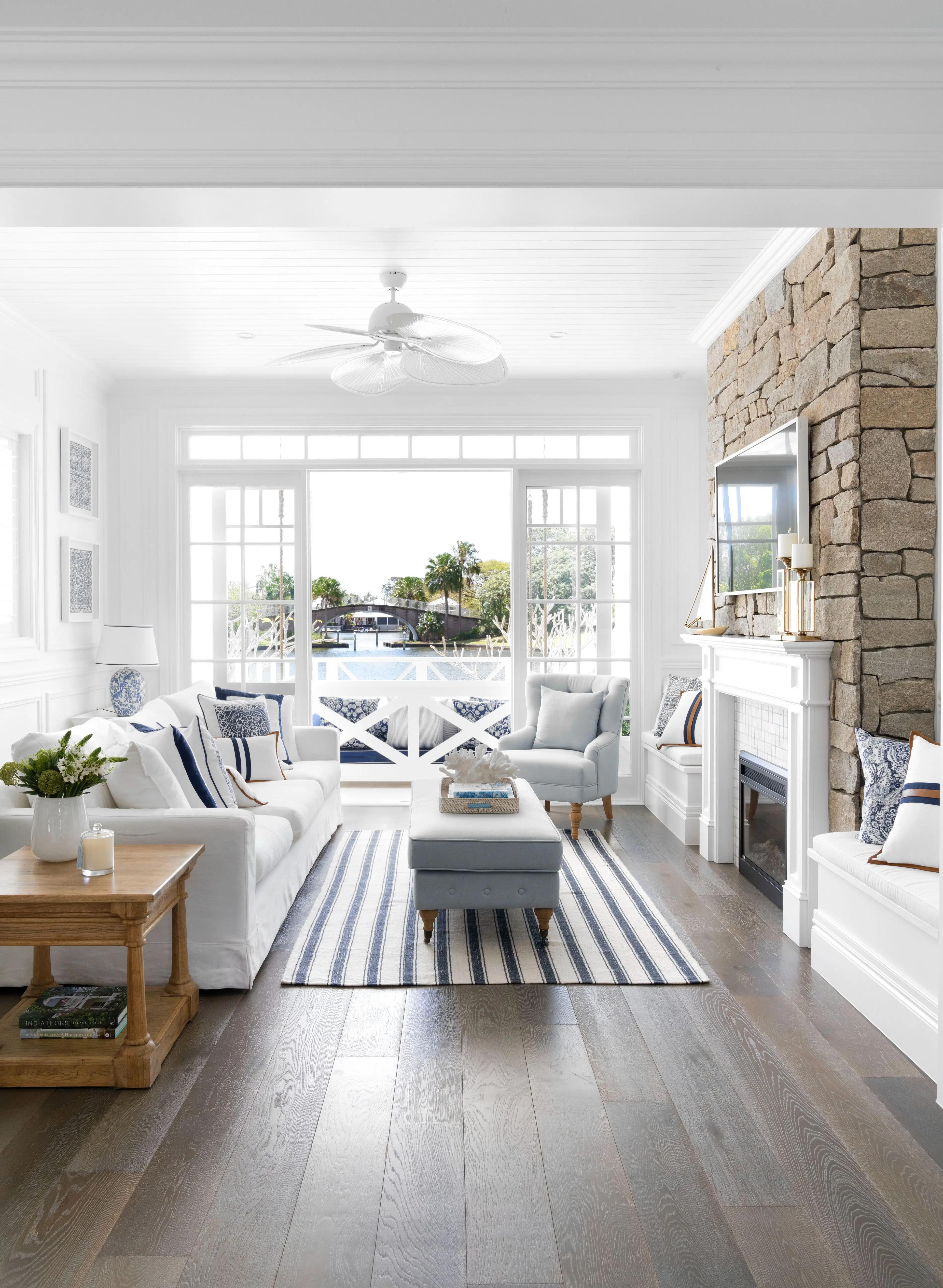 Coastal living room with stone fireplace and waterway view