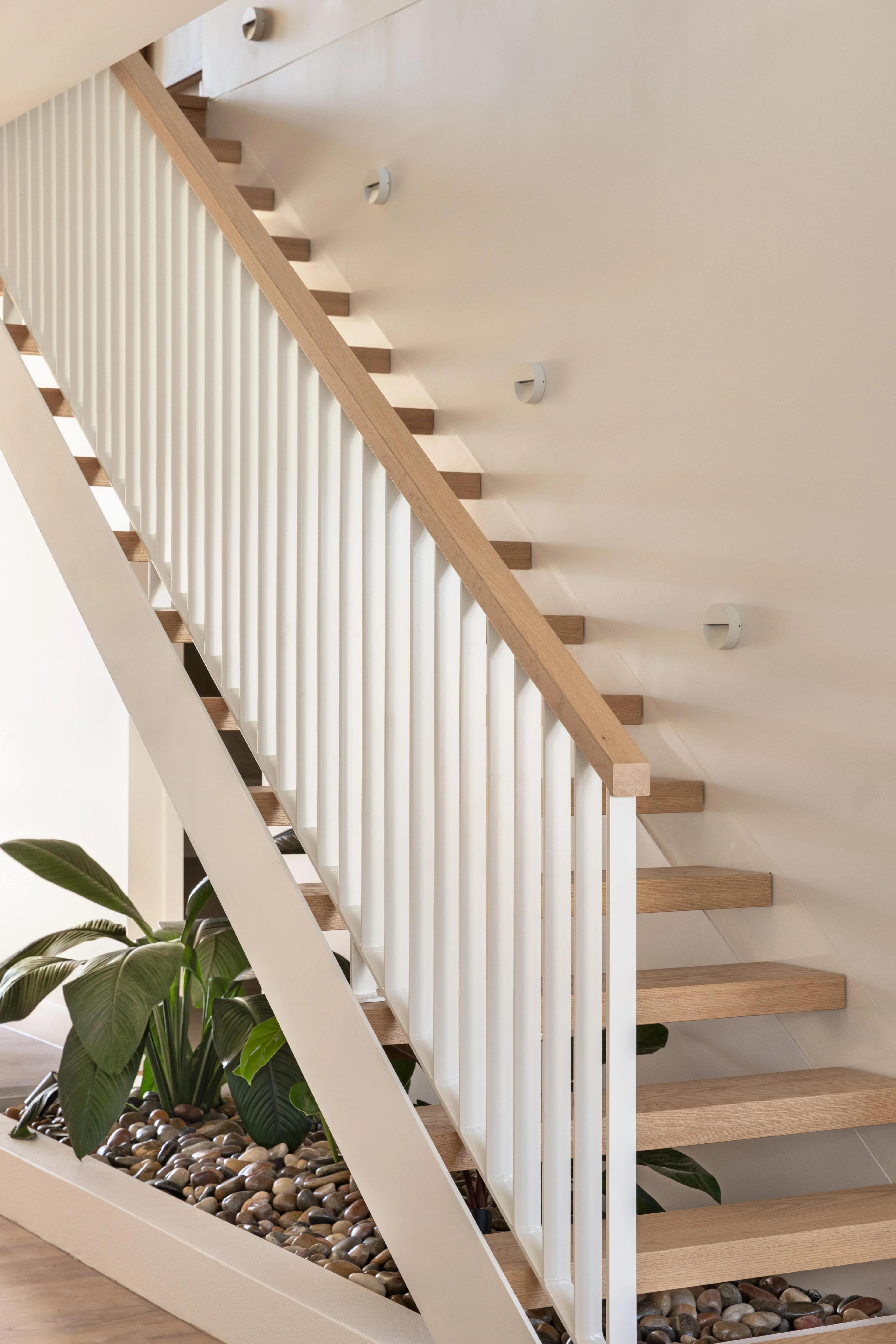 Timber staircase with white balustrade and pebble planter