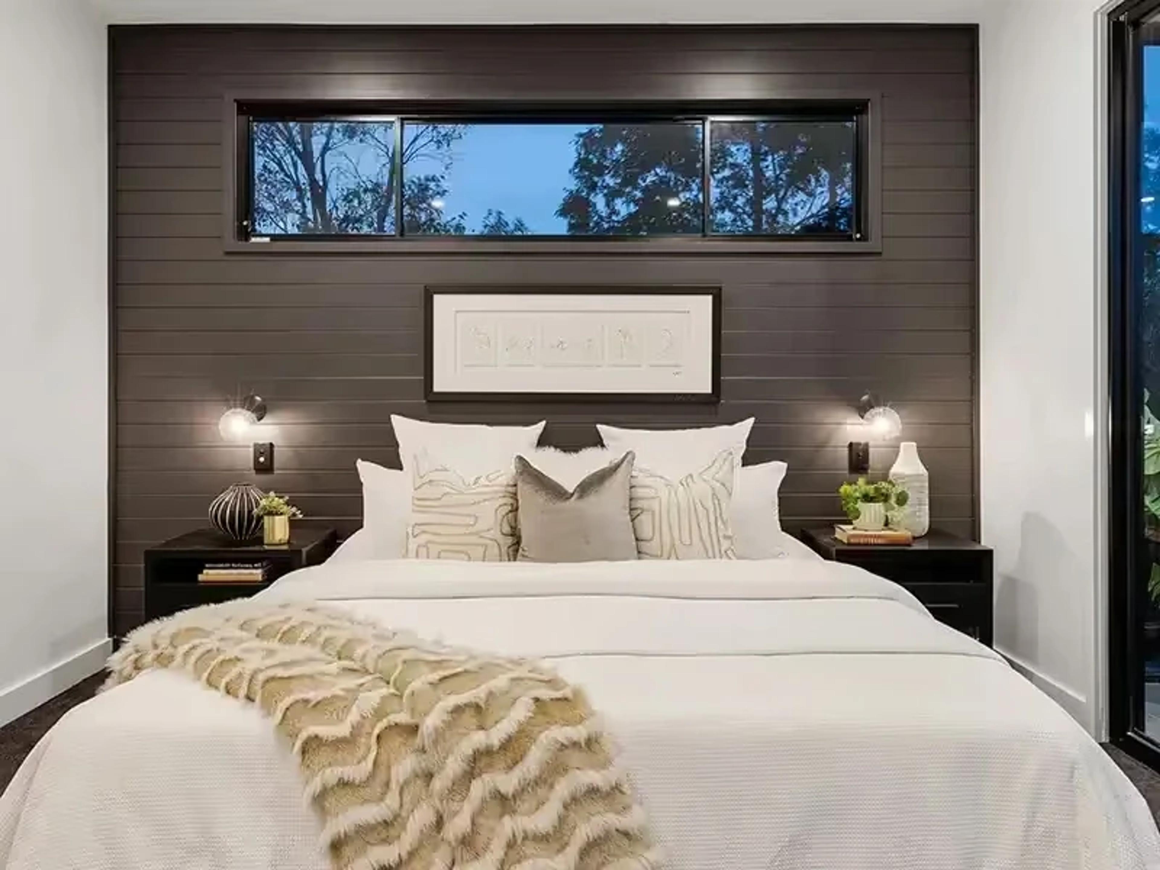 Bedroom with dark timber feature wall and high window