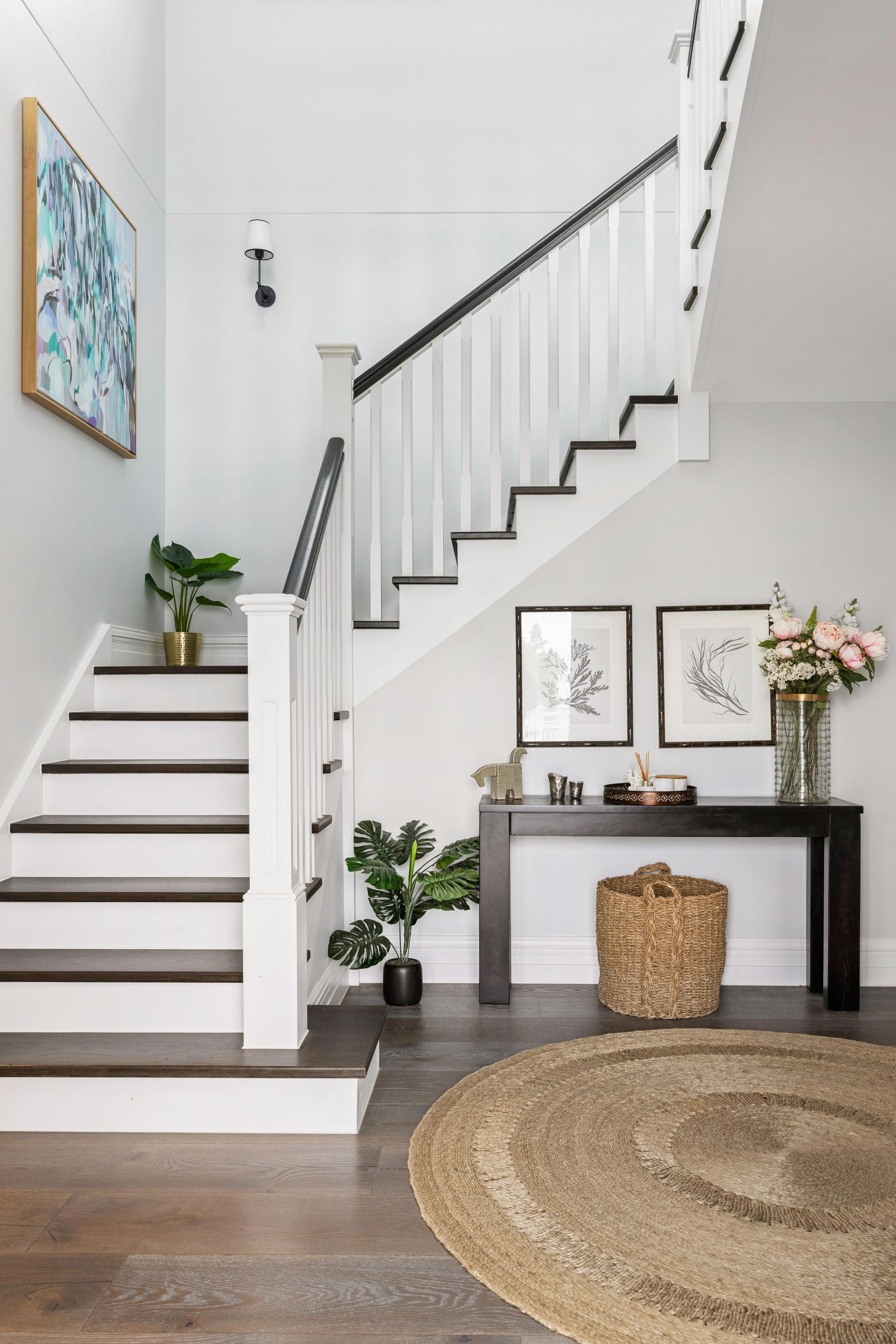Entry foyer with white timber staircase, dark treads and console table