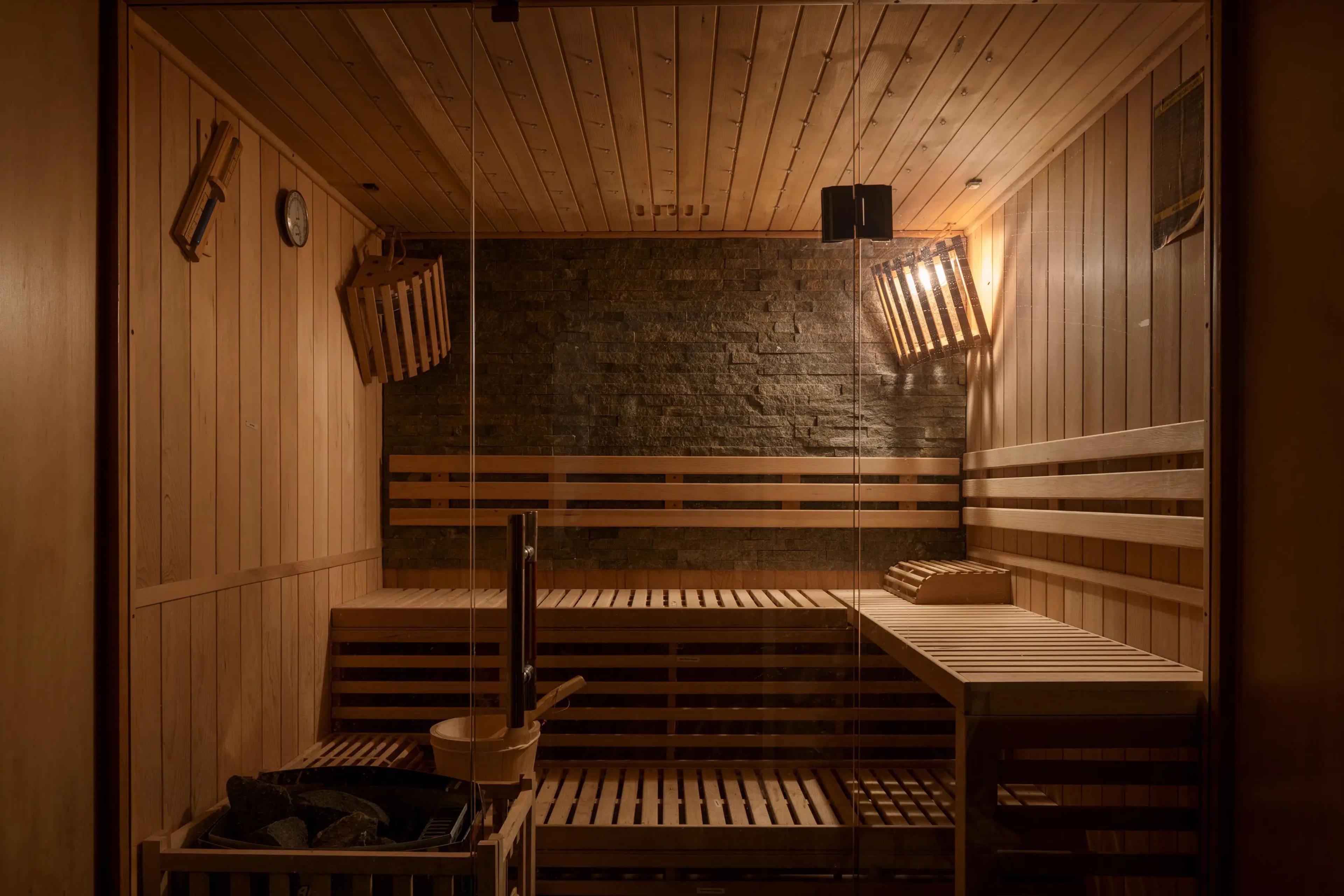 Timber lined sauna with glass door and stone feature wall