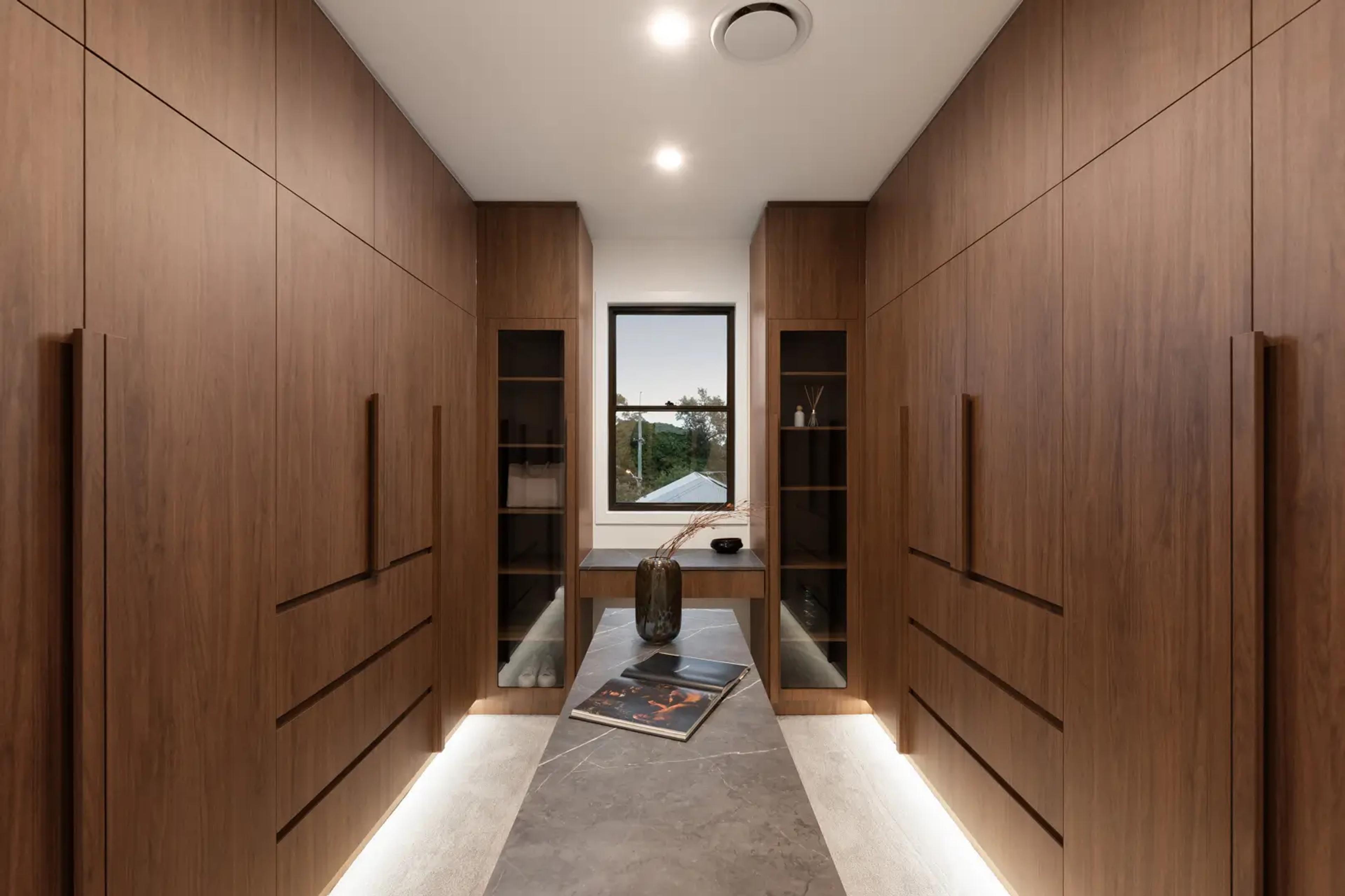 Walk in wardrobe with timber joinery and dresser