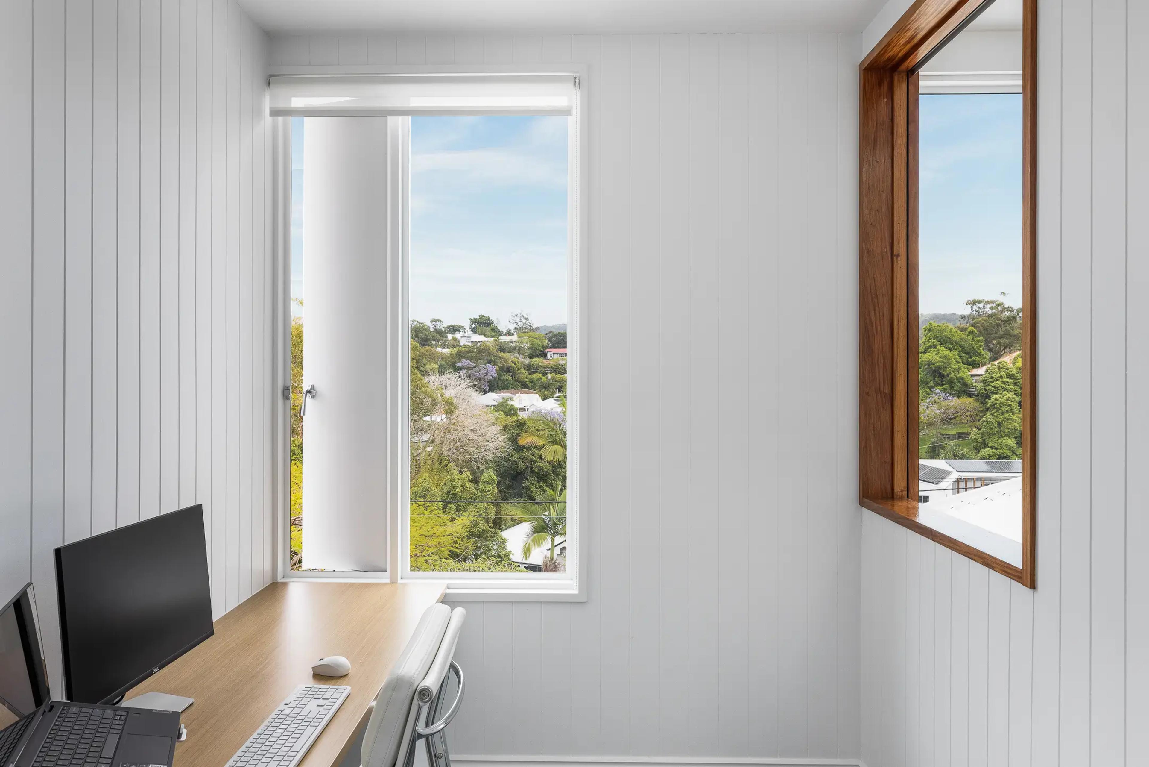 Home office with timber desk and leafy suburban view