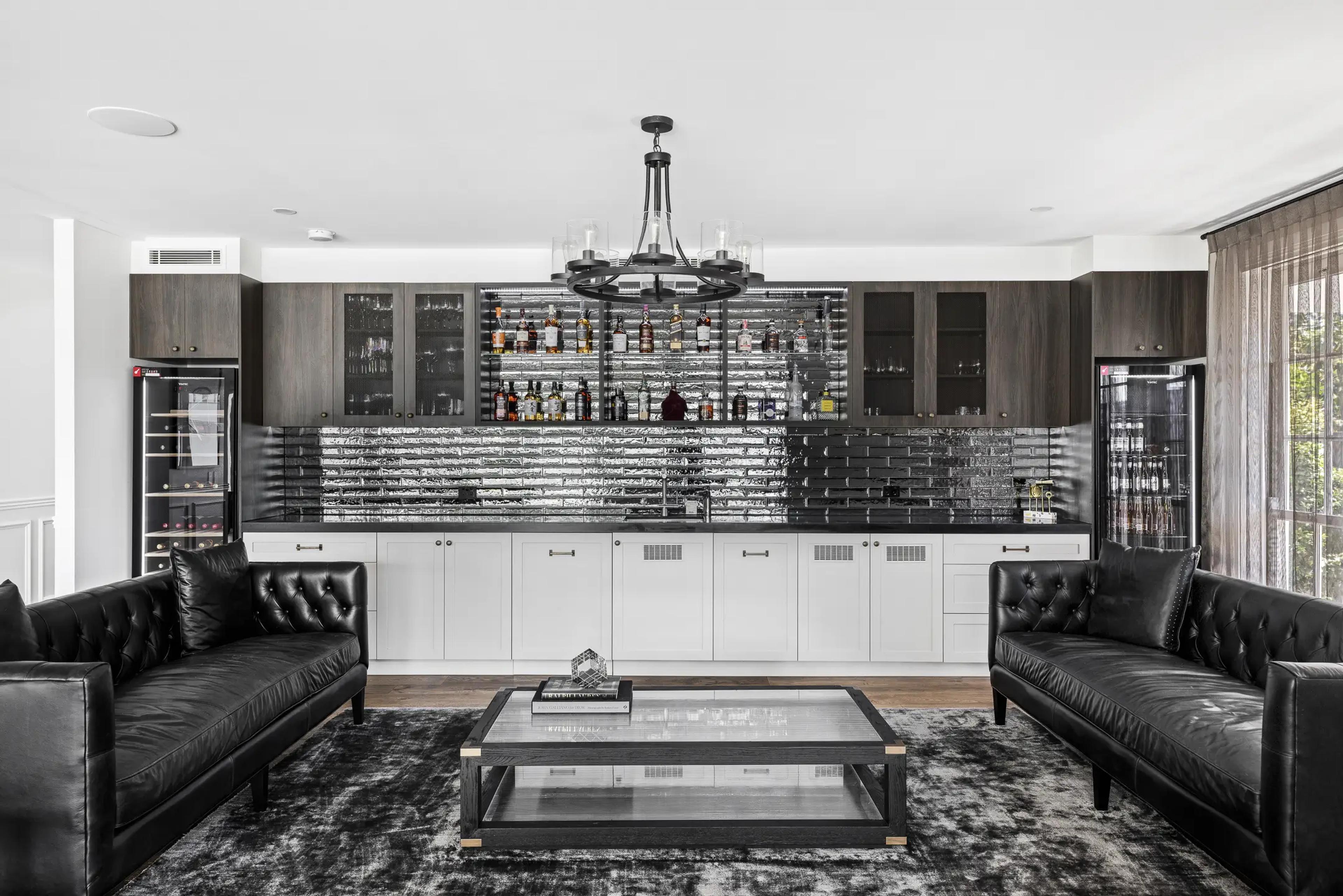 Bar lounge with mirrored shelving and black leather sofas