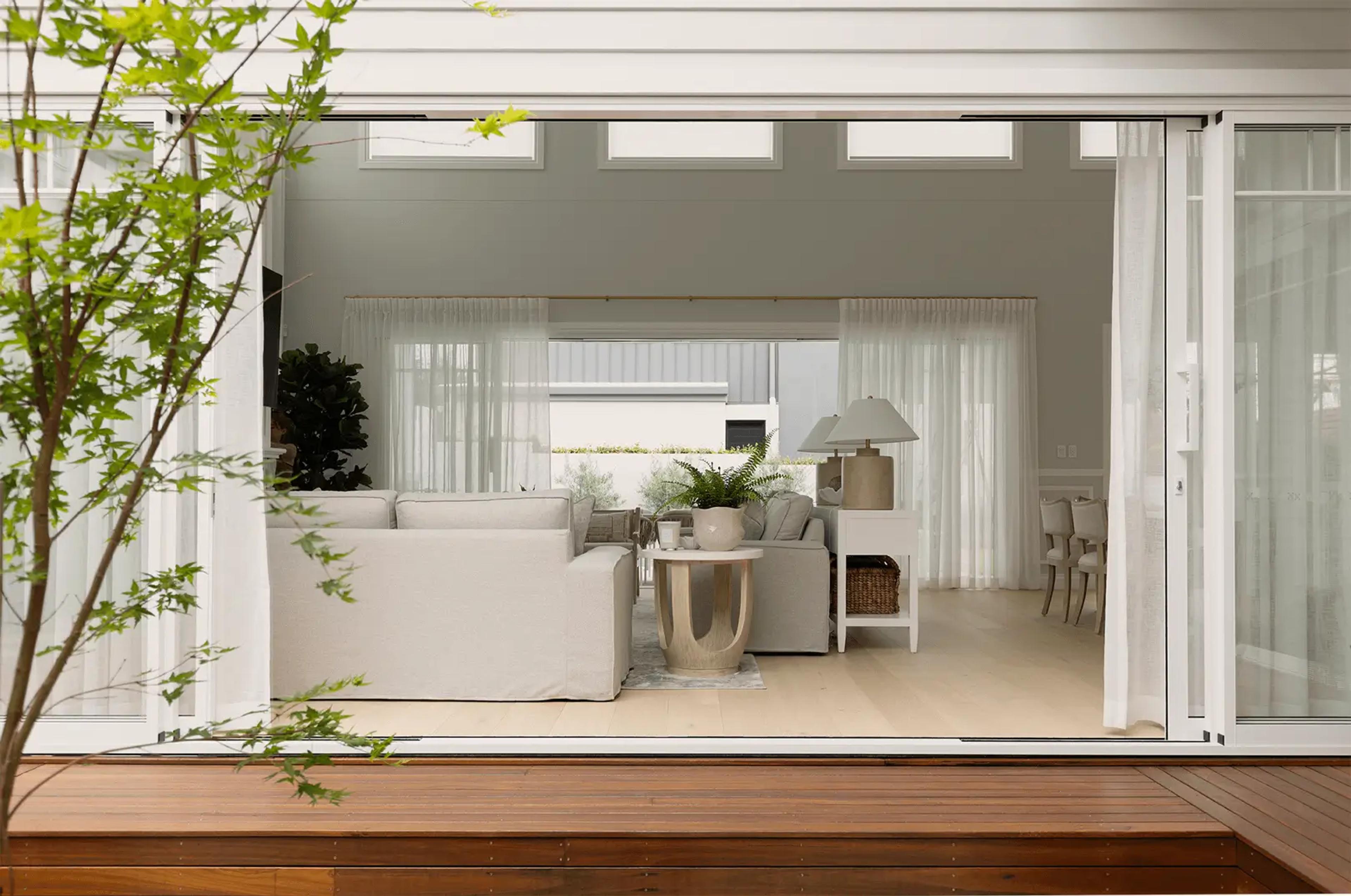Living room opening onto courtyard deck through glass doors