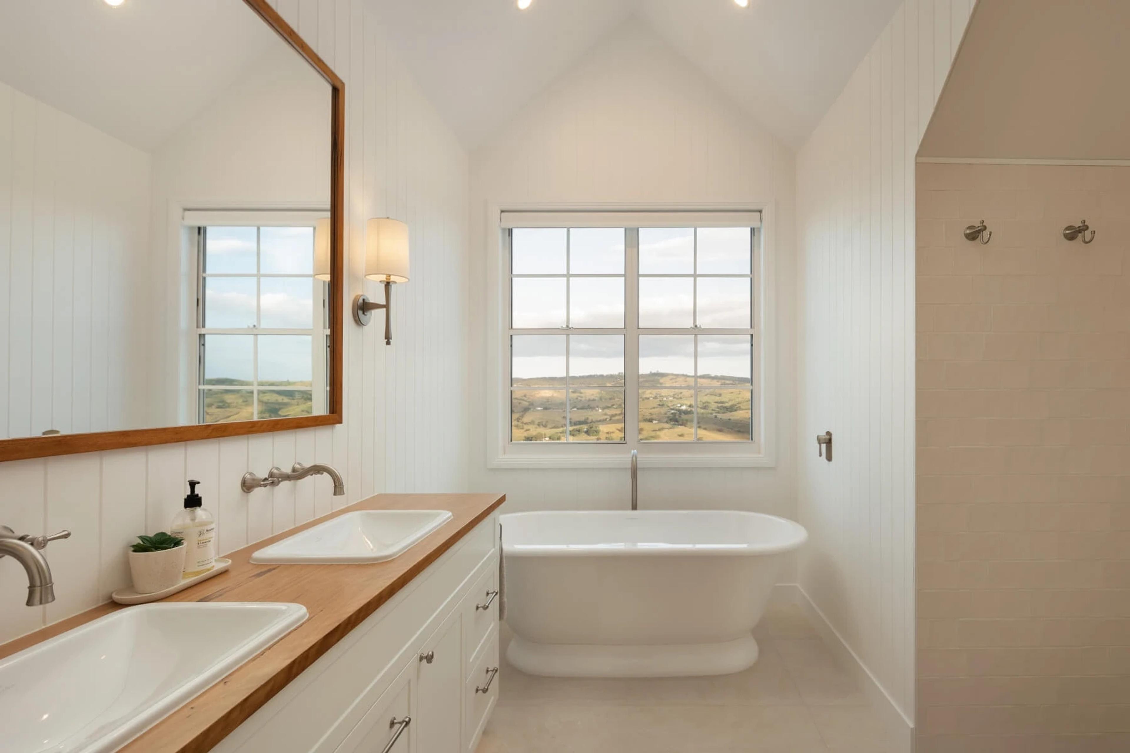 Bathroom with freestanding bath and window framing countryside