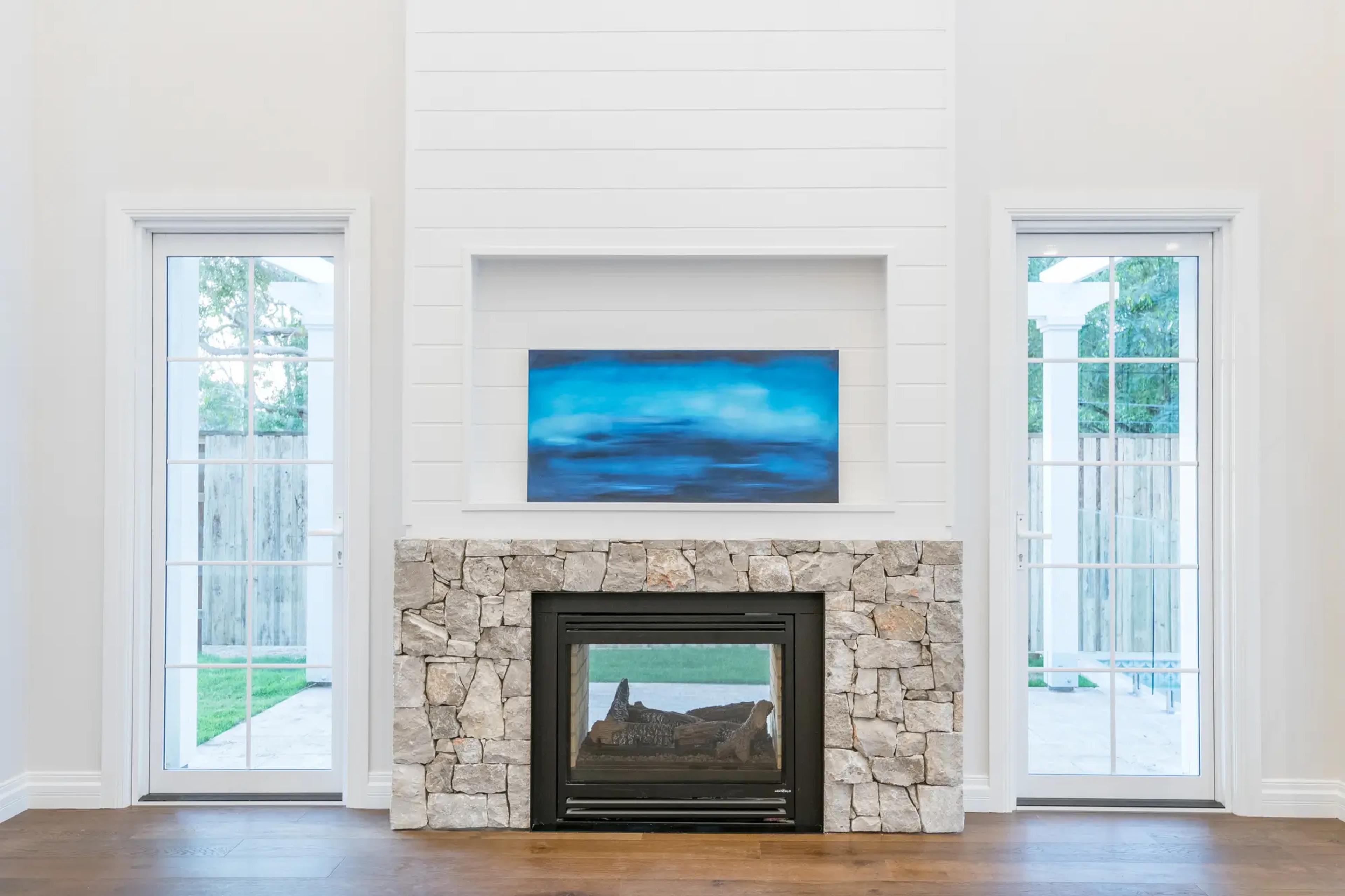 Living room with stone fireplace flanked by french doors