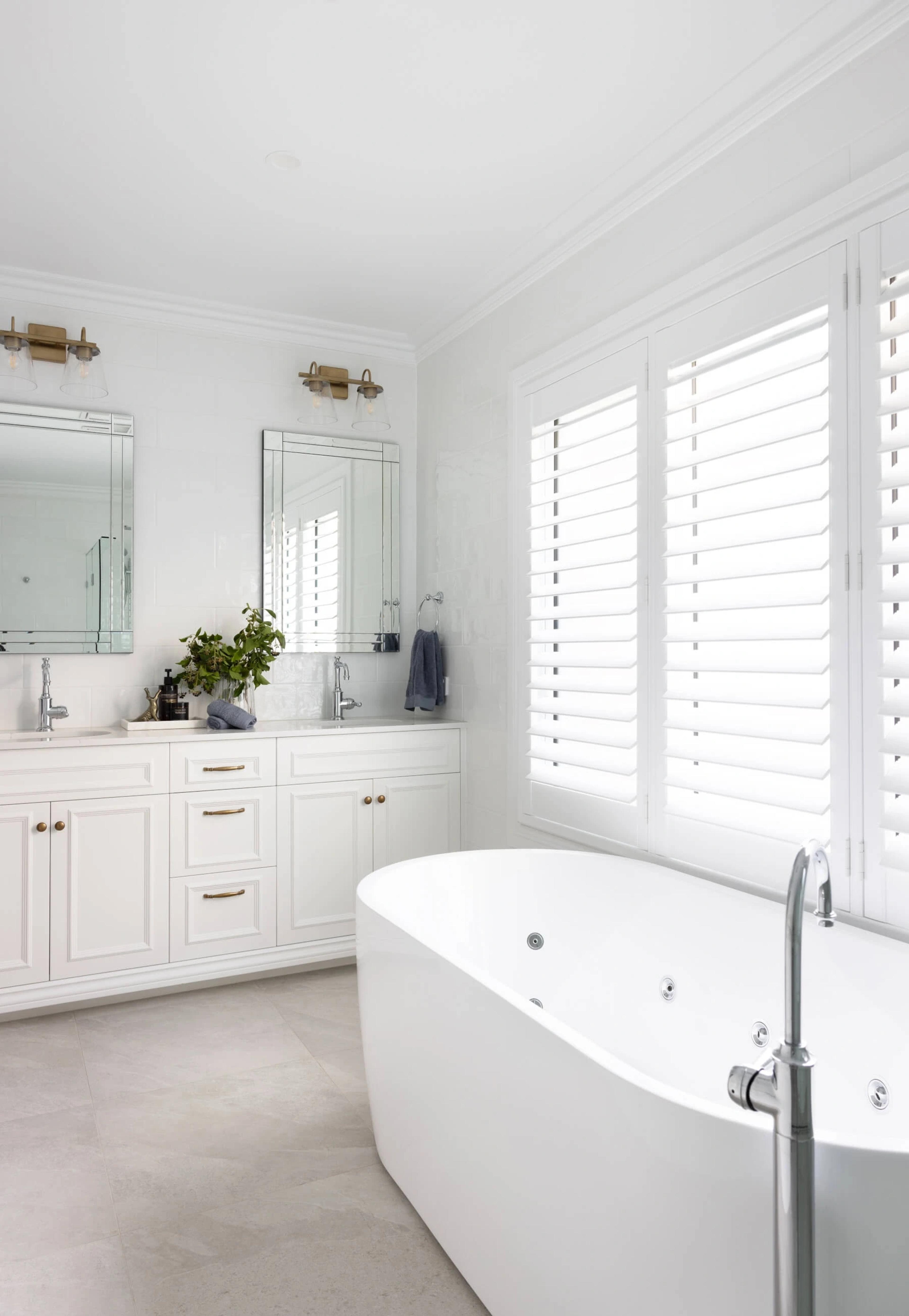White ensuite with freestanding bath and plantation shutters