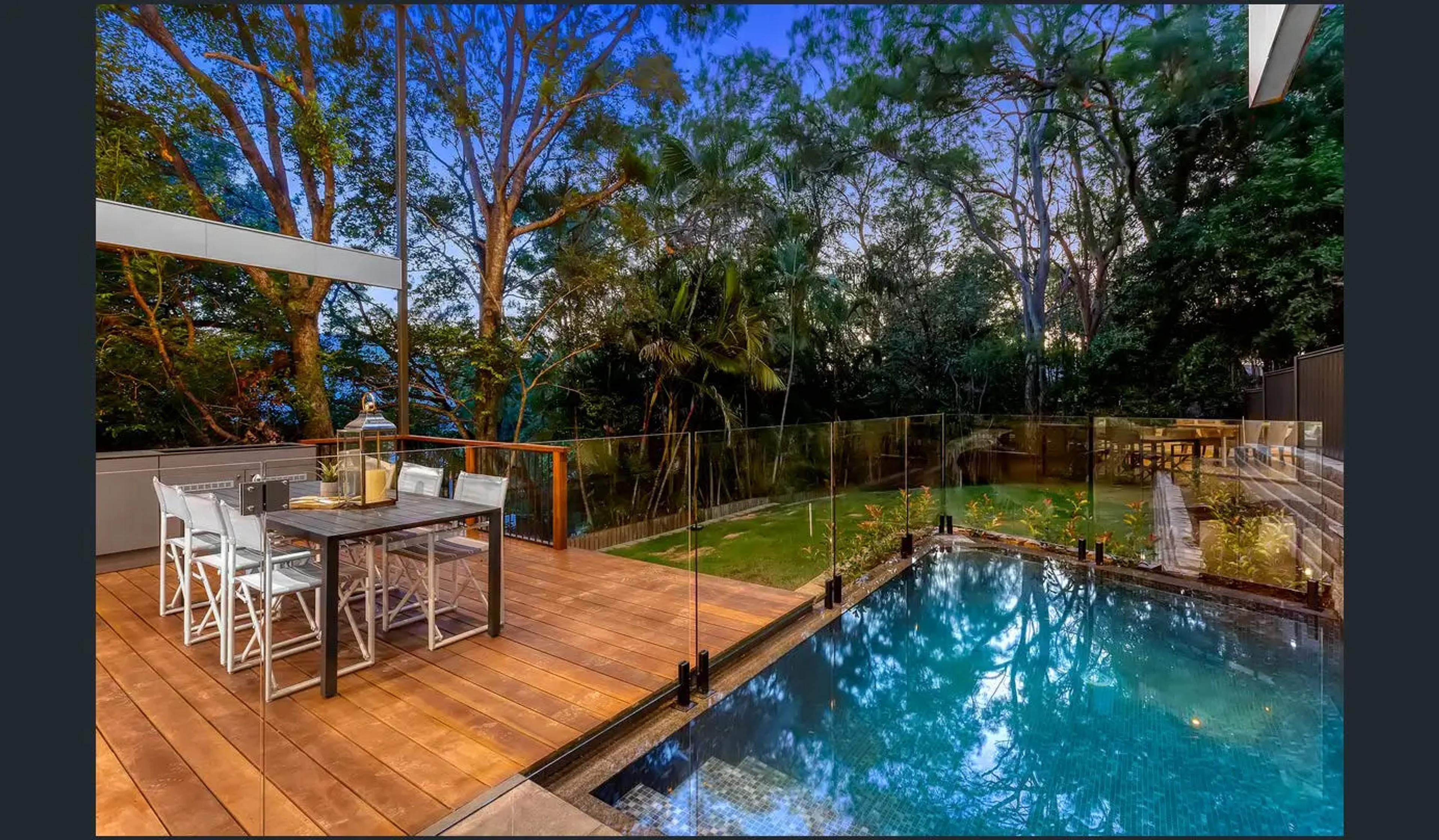 Backyard pool and timber deck surrounded by rainforest trees
