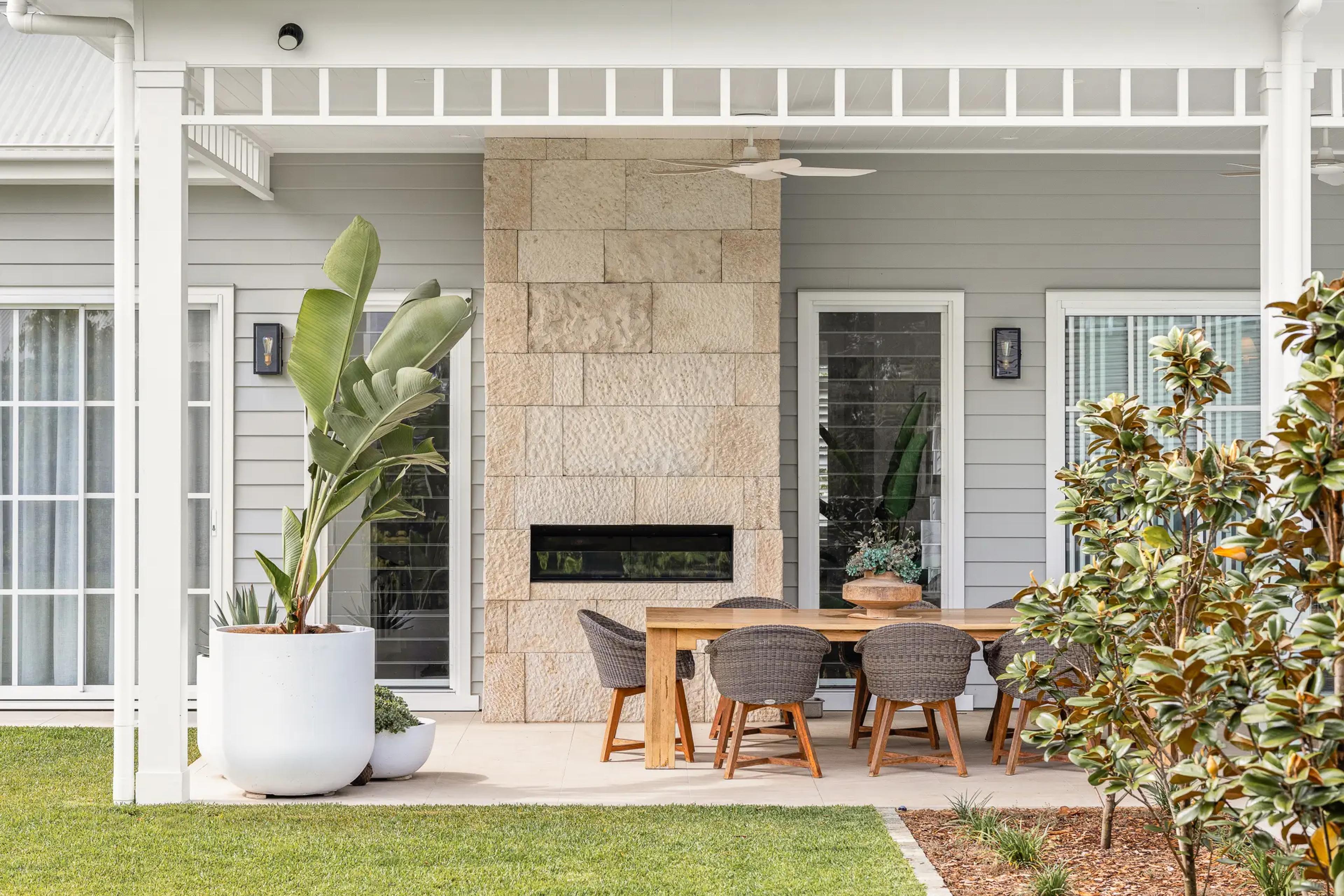 Alfresco dining area with stone fireplace and weatherboard exterior