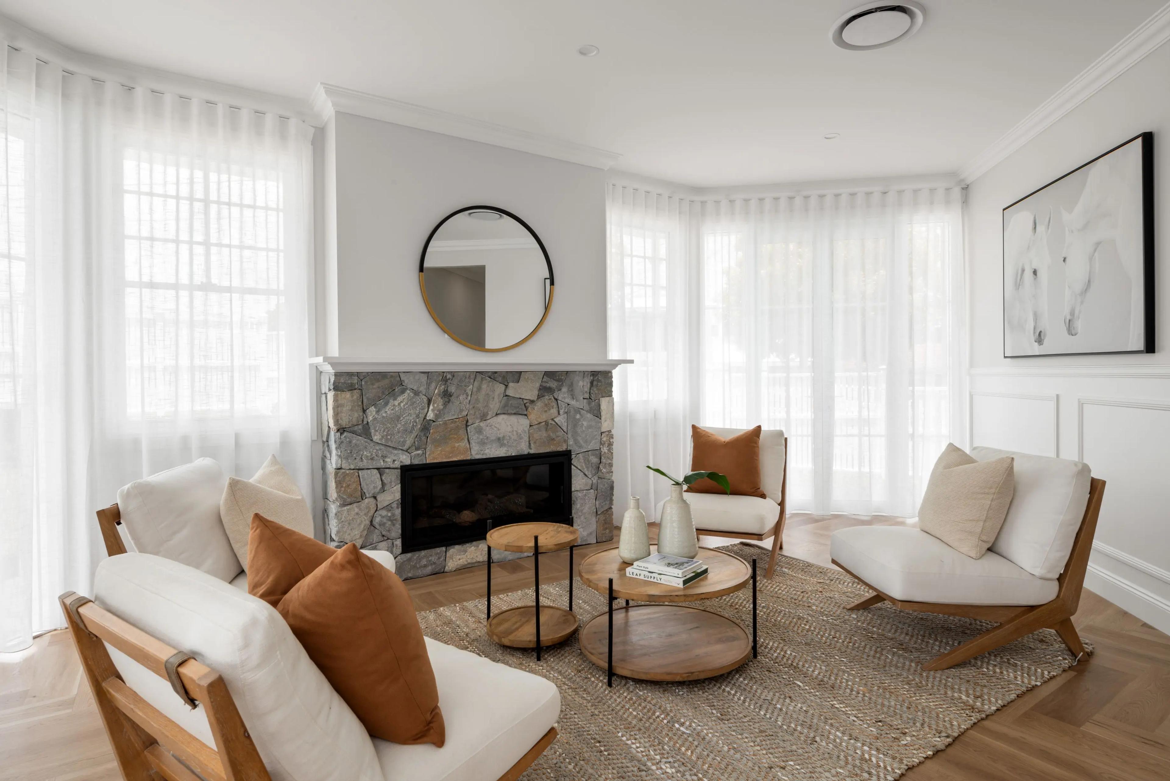 Lounge room with stone fireplace, round mirror and armchairs