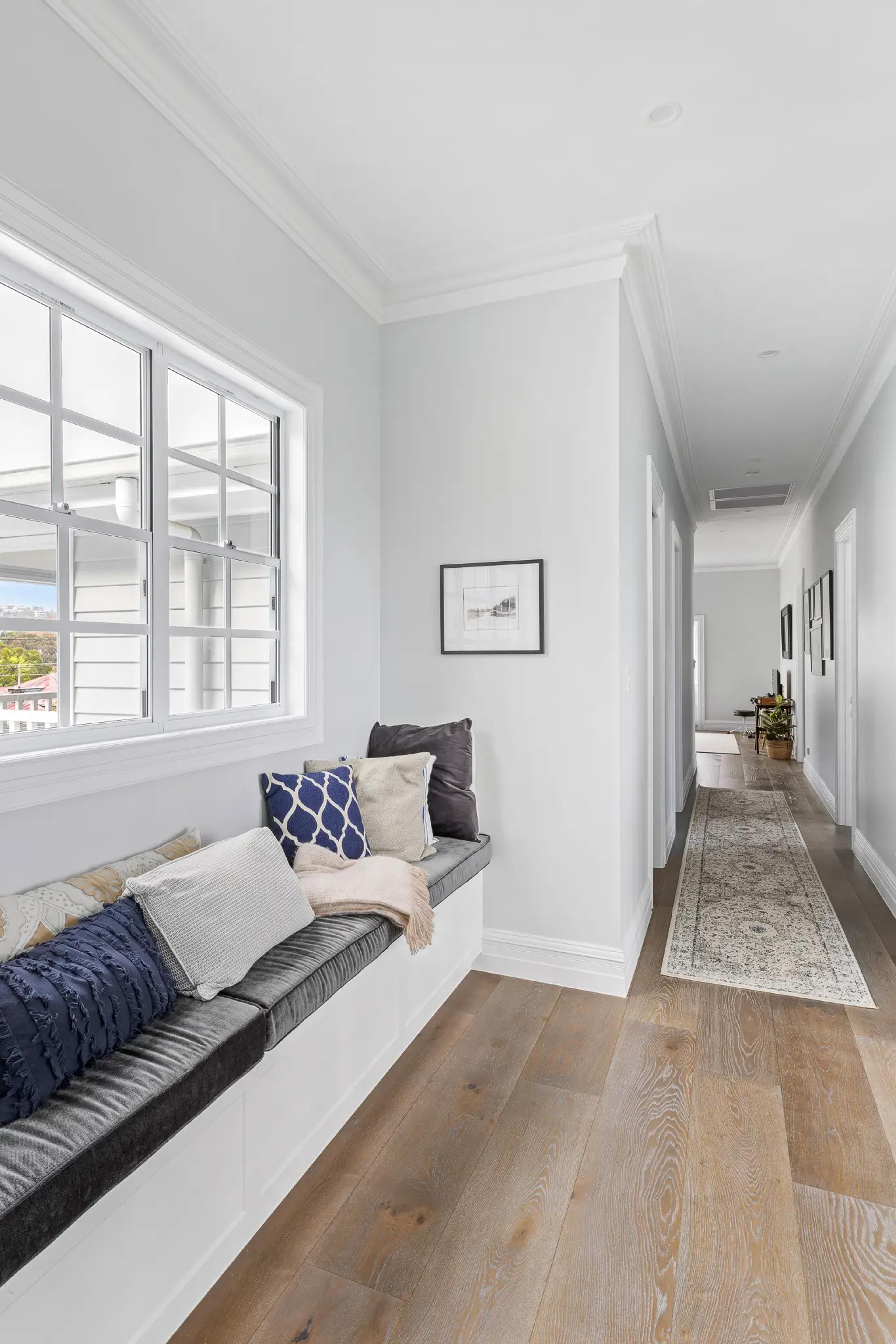 Hallway with cushioned window seat and timber floorboards