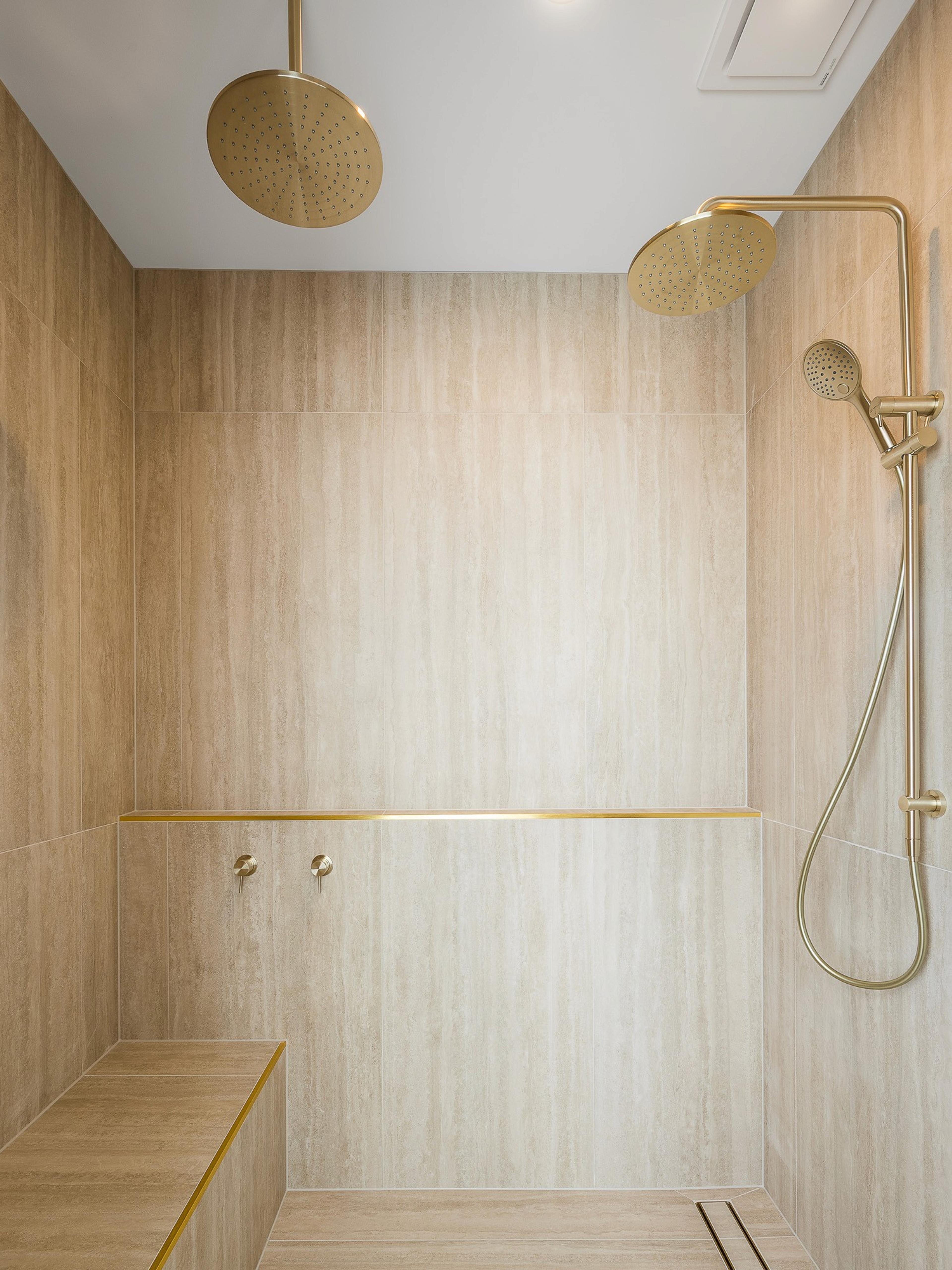 Double shower with brass fittings and stone tiling