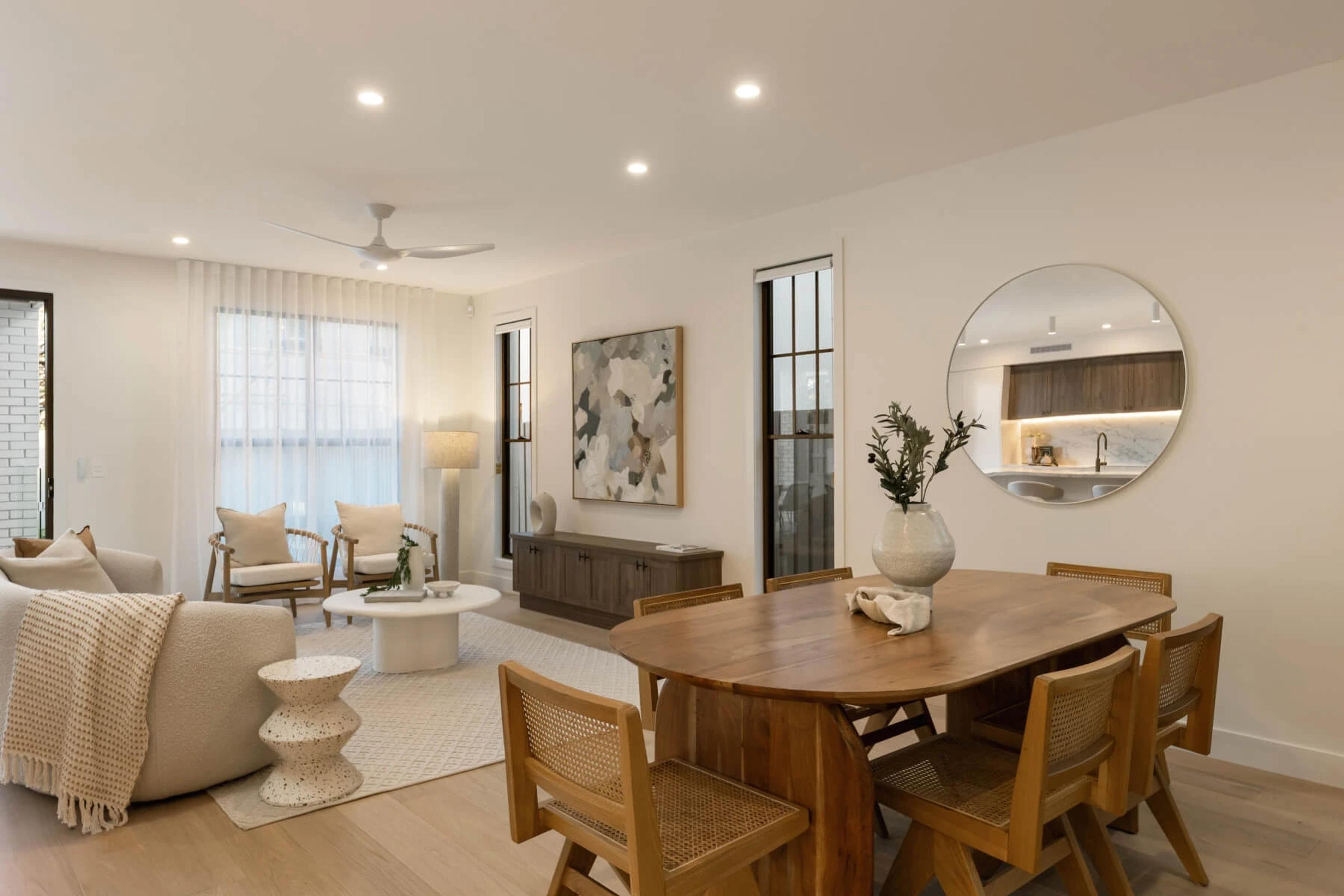 Combined living and dining space with round mirror and timber furniture