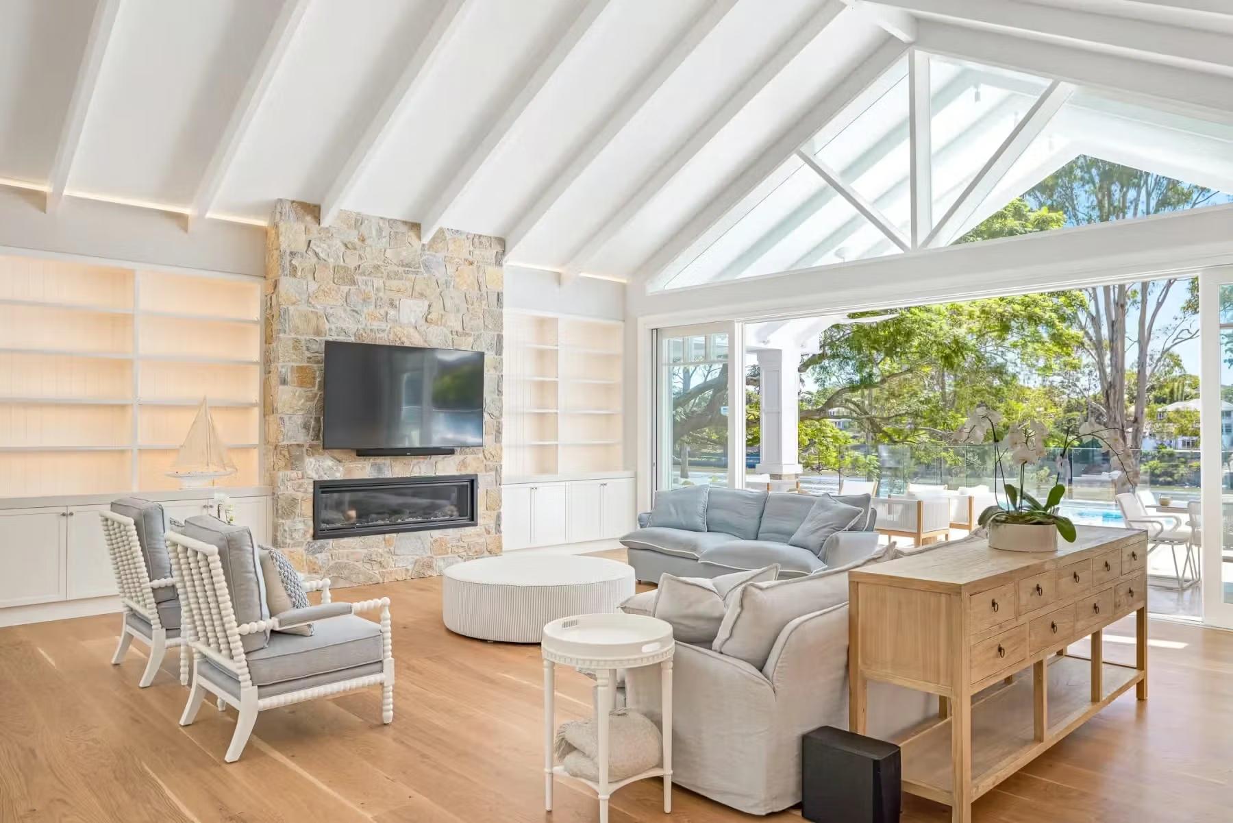Living room with a stone fireplace and vaulted ceiling at Jacaranda House, designed by Invilla Architecture