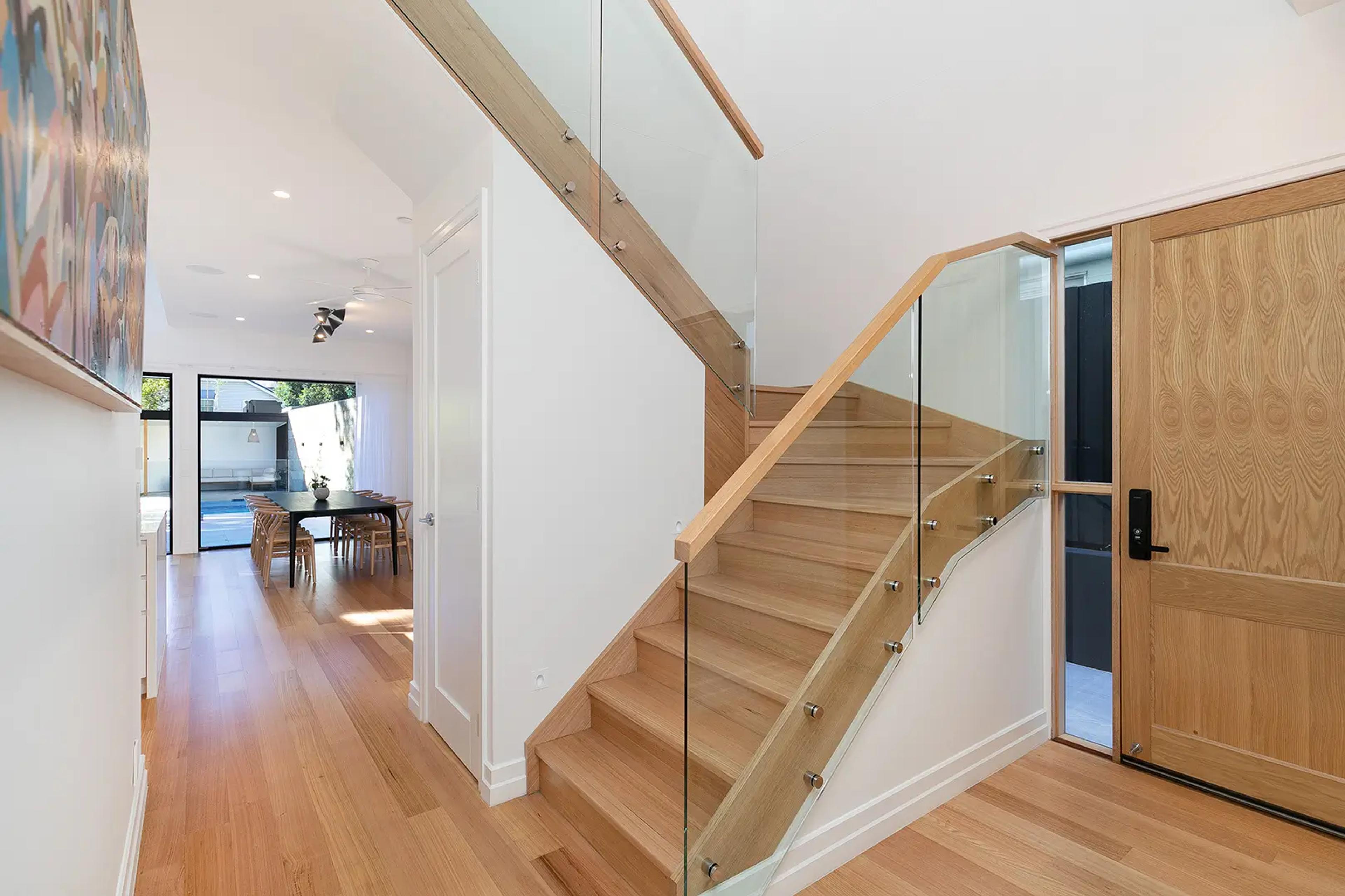 Entry foyer with timber staircase, glass balustrade and front door