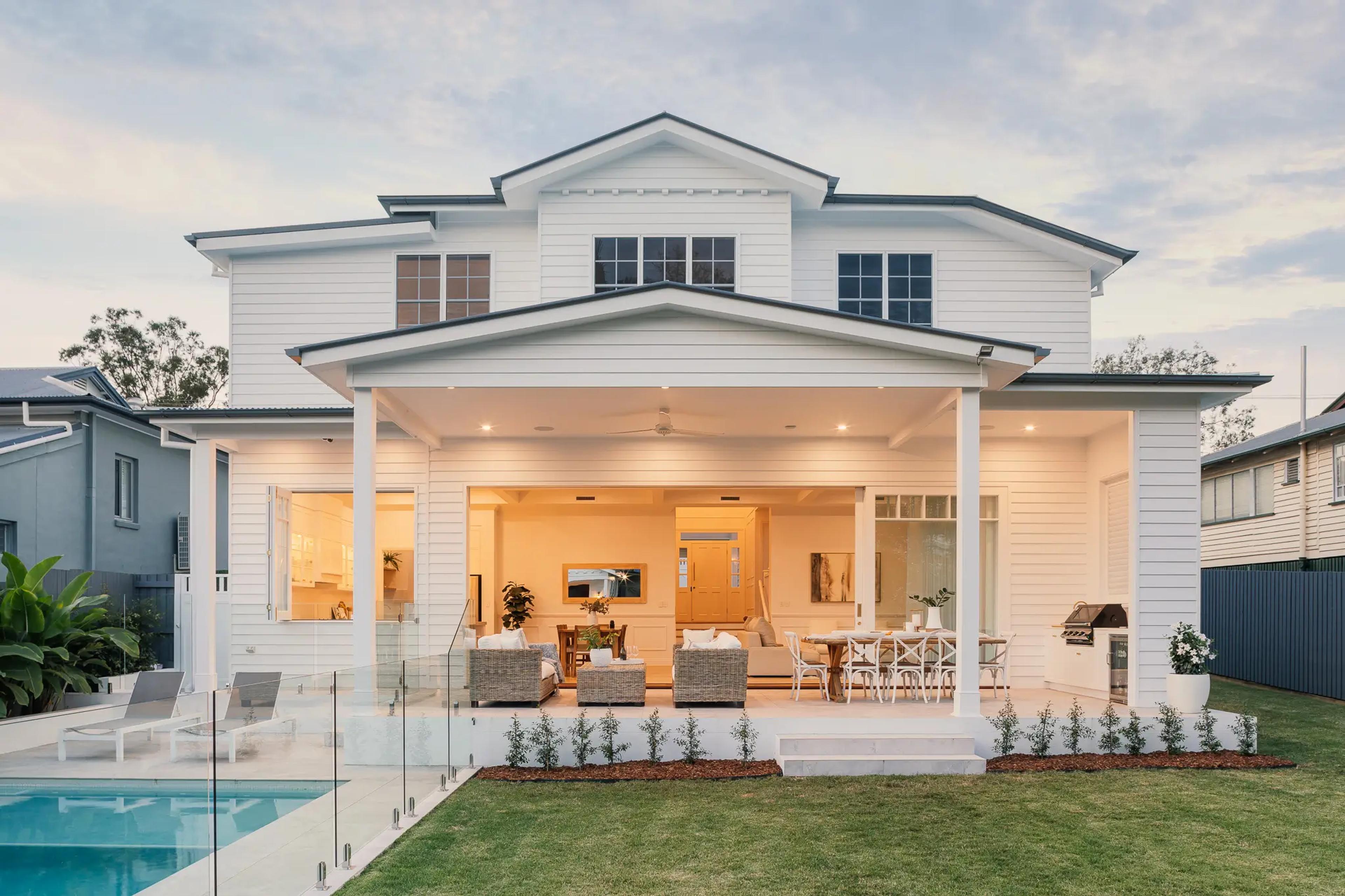 Rear elevation of white home over covered patio and pool