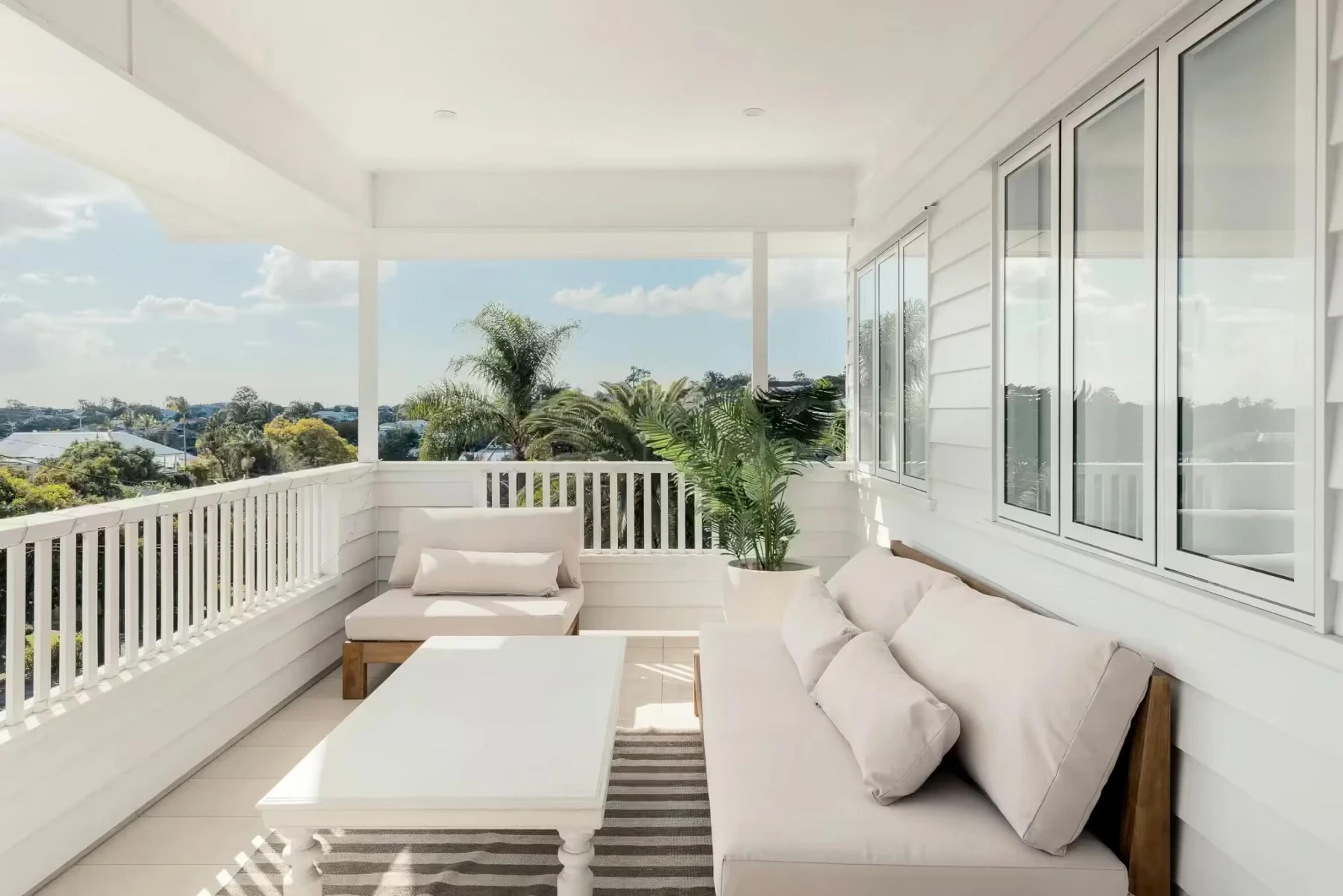 Covered balcony with white sofa and treetop views