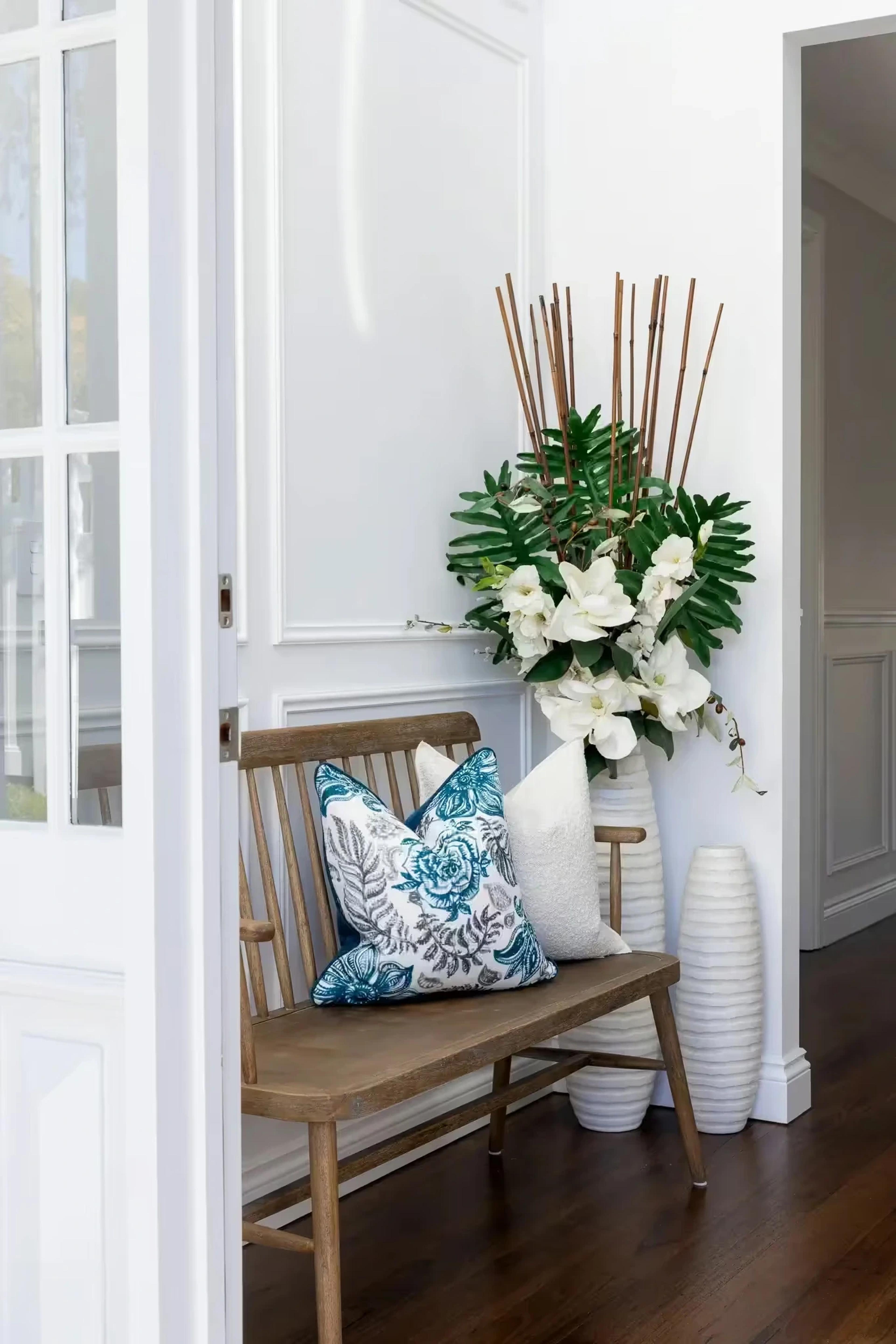 Hallway bench with cushions and white floral vases