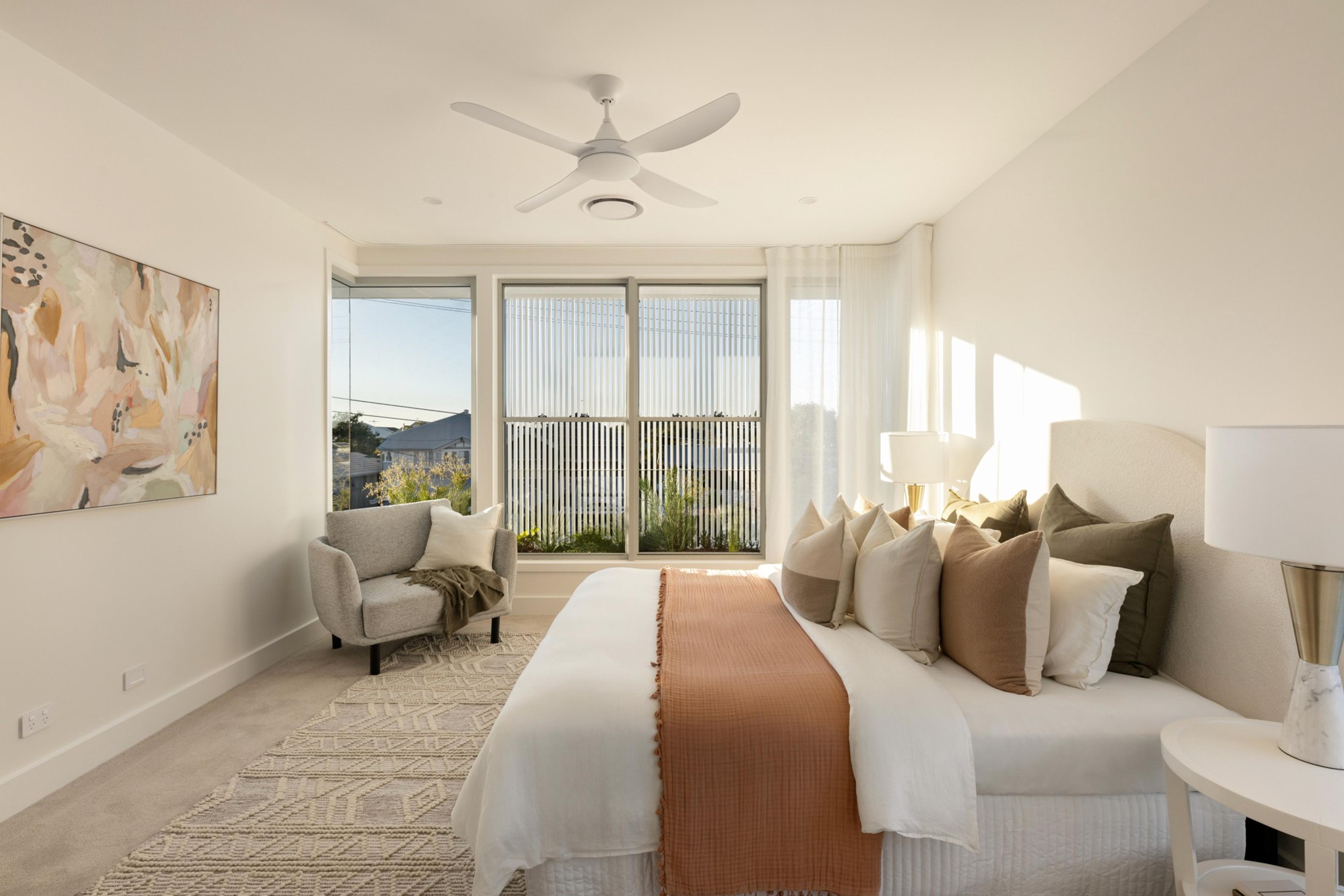 Main bedroom with corner windows and neutral styling