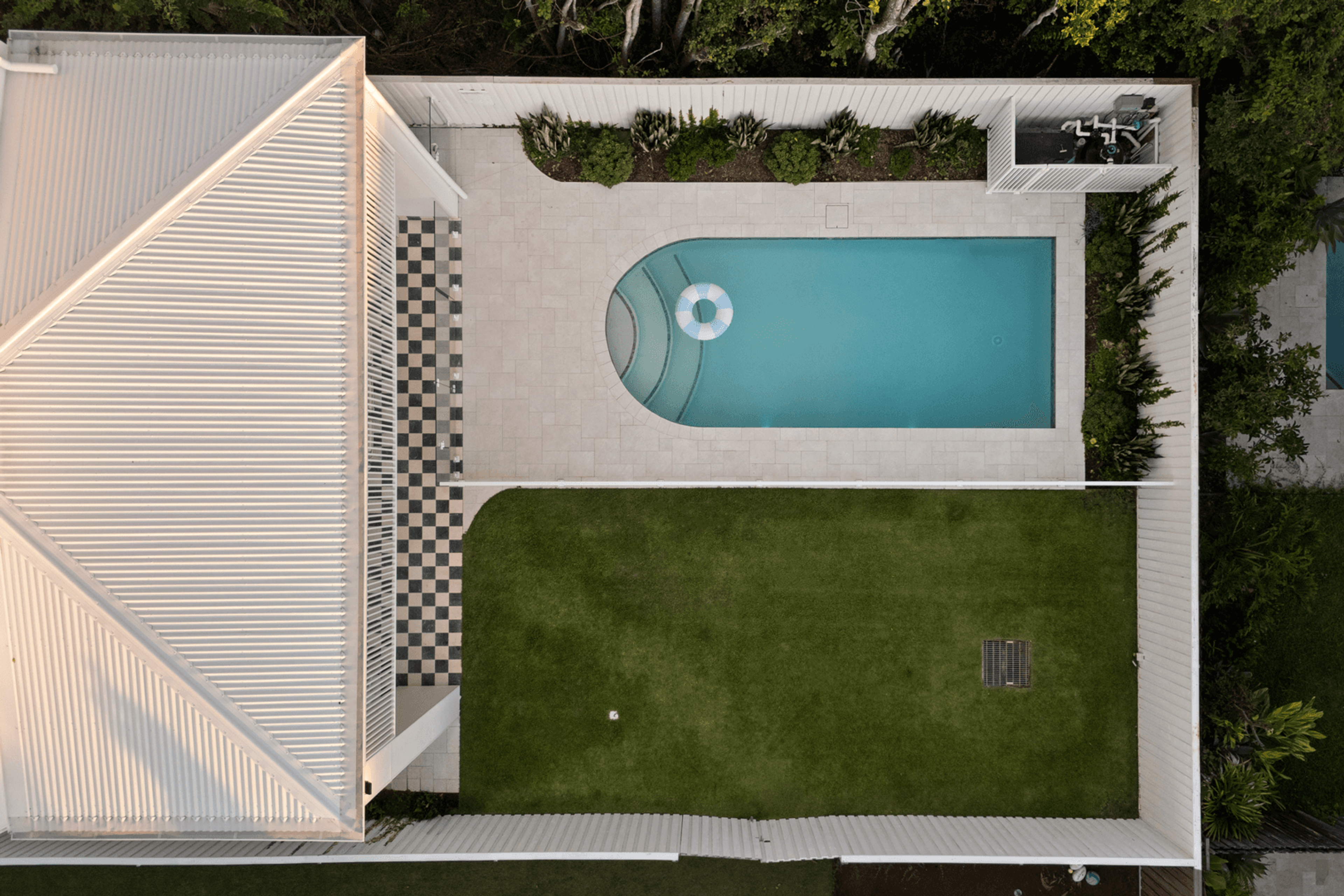 Aerial view of rear pool, lawn and white roof